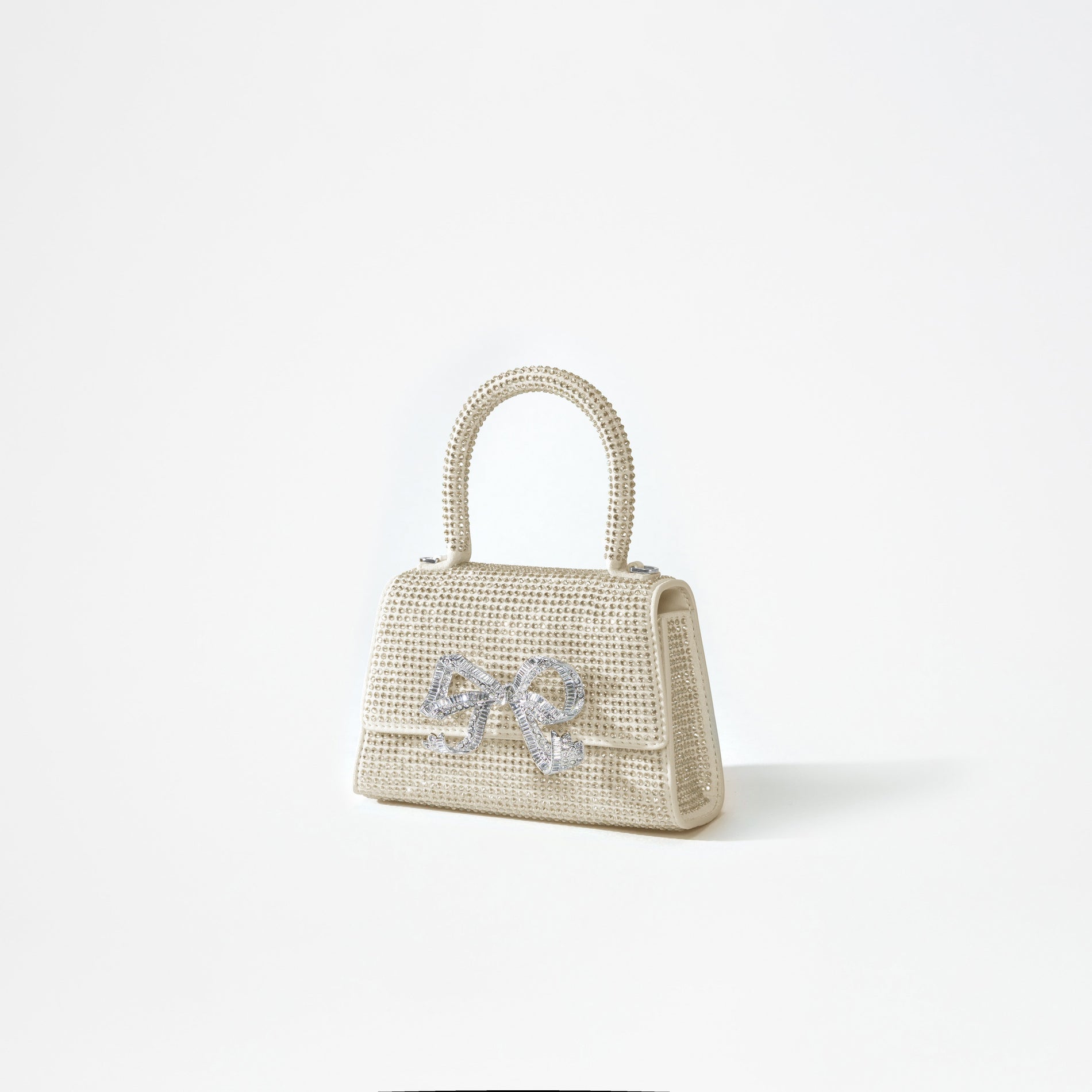 A woman wearing the Cream Rhinestone Bow Micro Bag