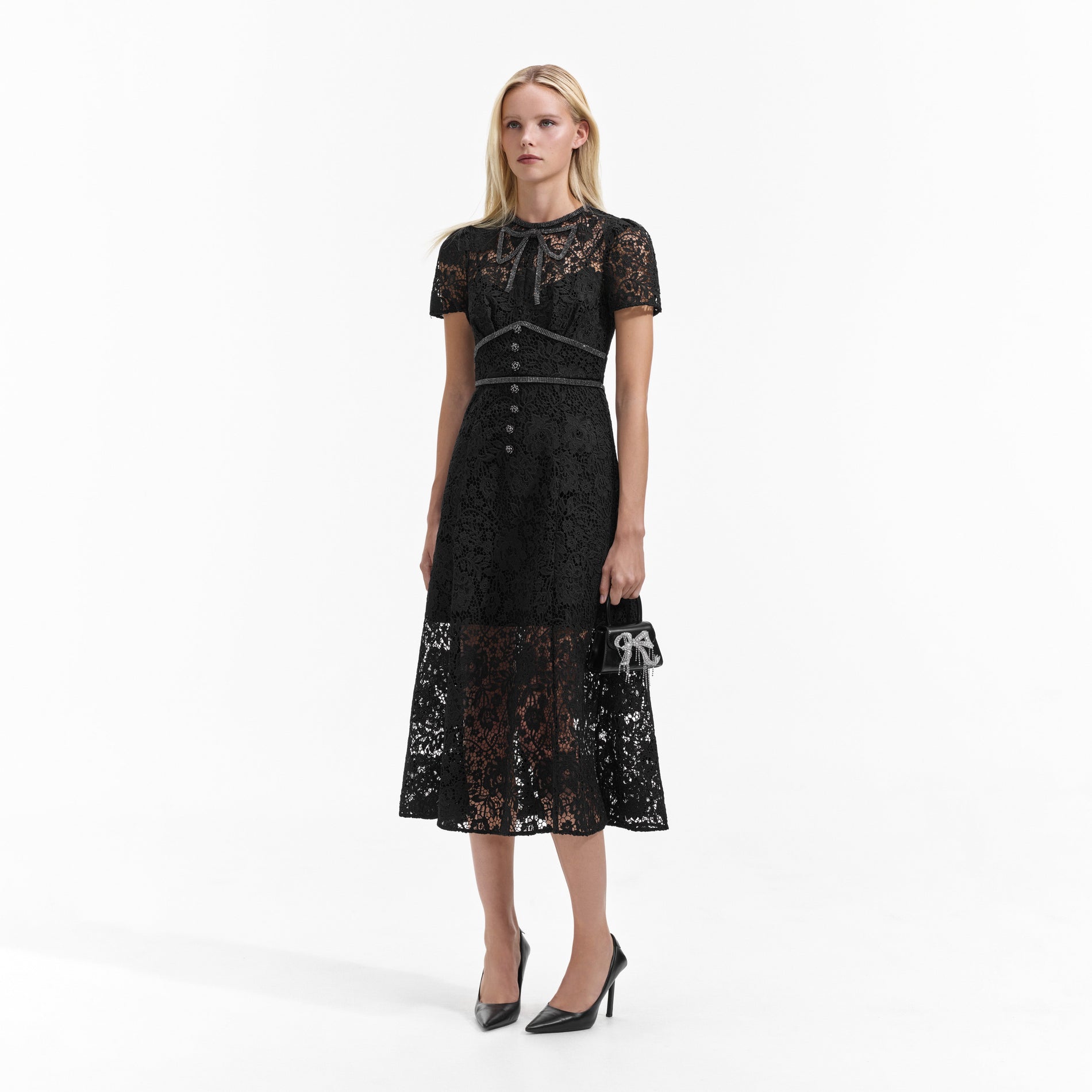 Side view of a woman wearing the Black Cord Lace Bow Midi Dress