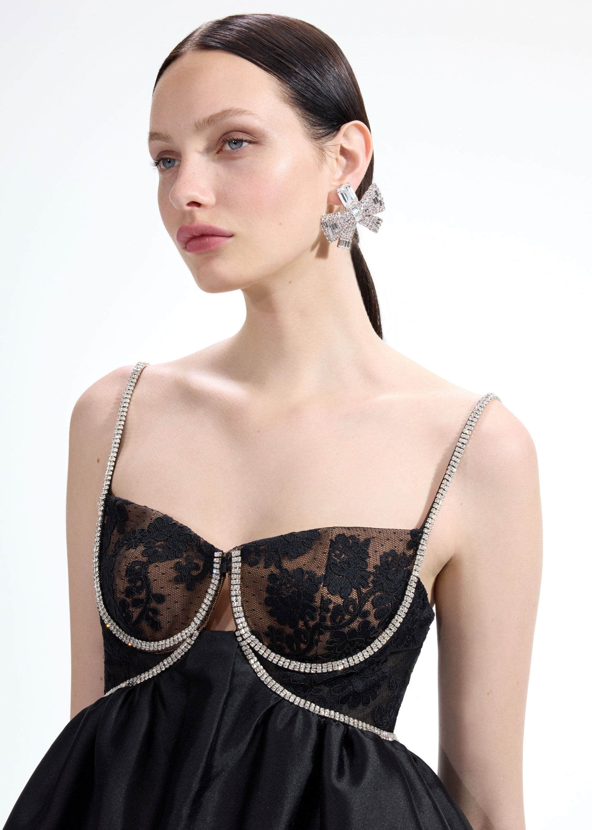 A close up of a woman wearing the Large Crystal Bow Earrings