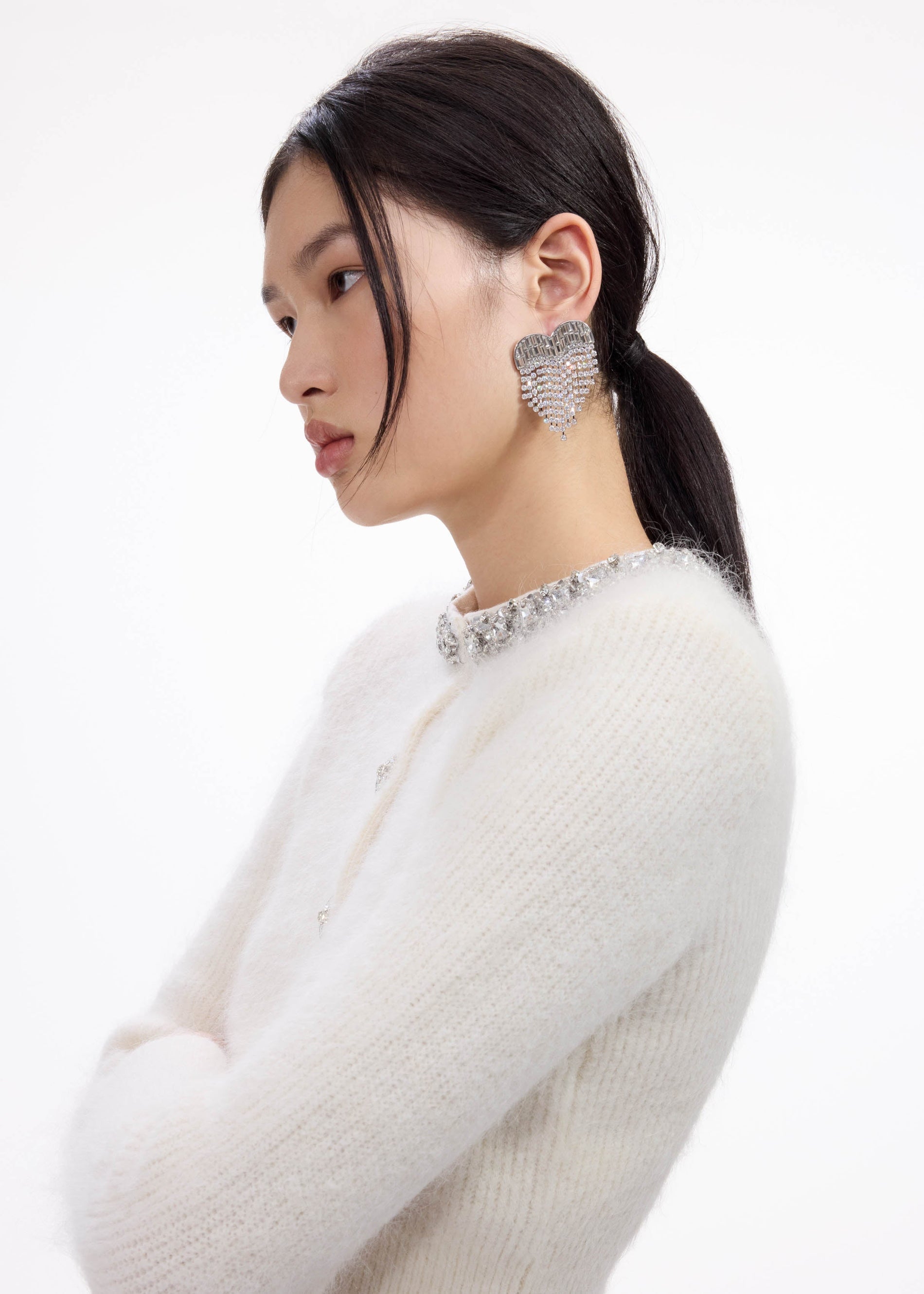 A close up of a woman wearing the Crystal Heart Earrings