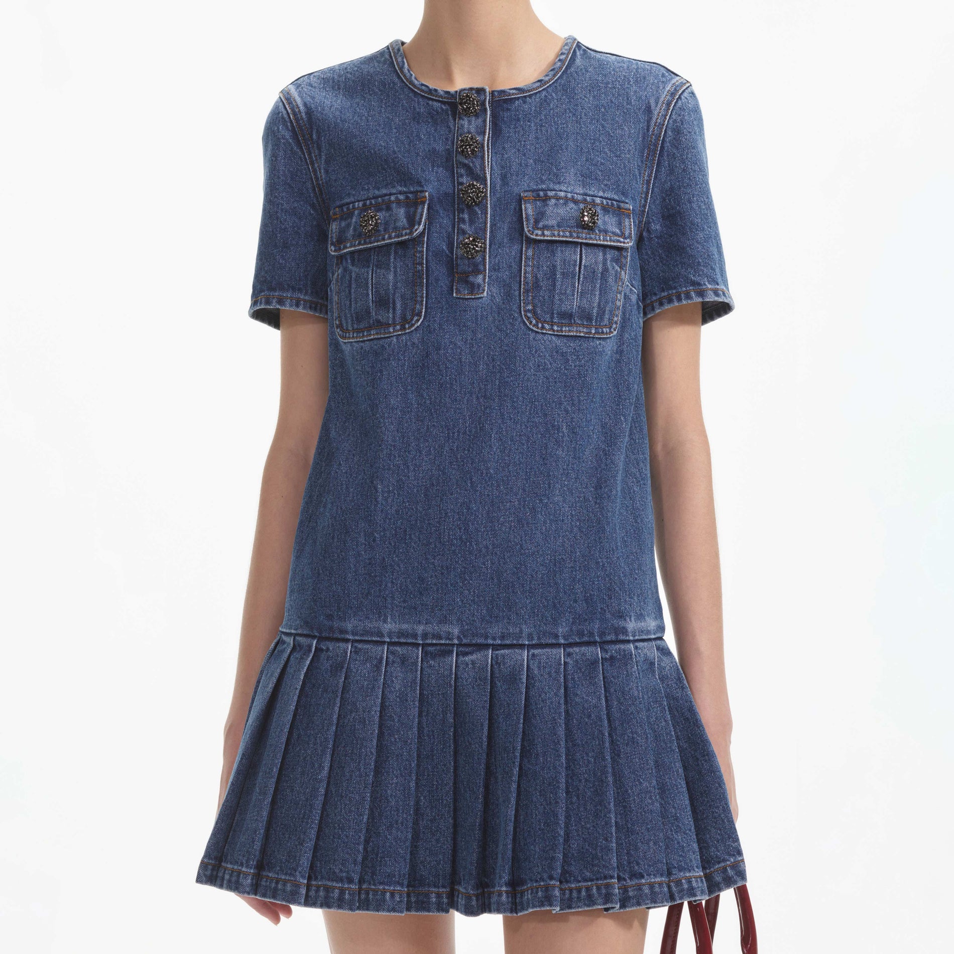 A close up of a woman wearing the Pleated Denim Mini Dress