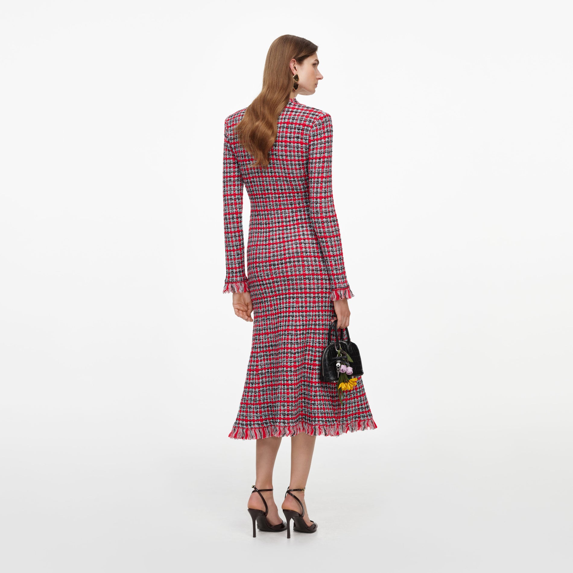 Woman in red, black, and white plaid dress with fringe hem, black heels, and black handbag with flowers