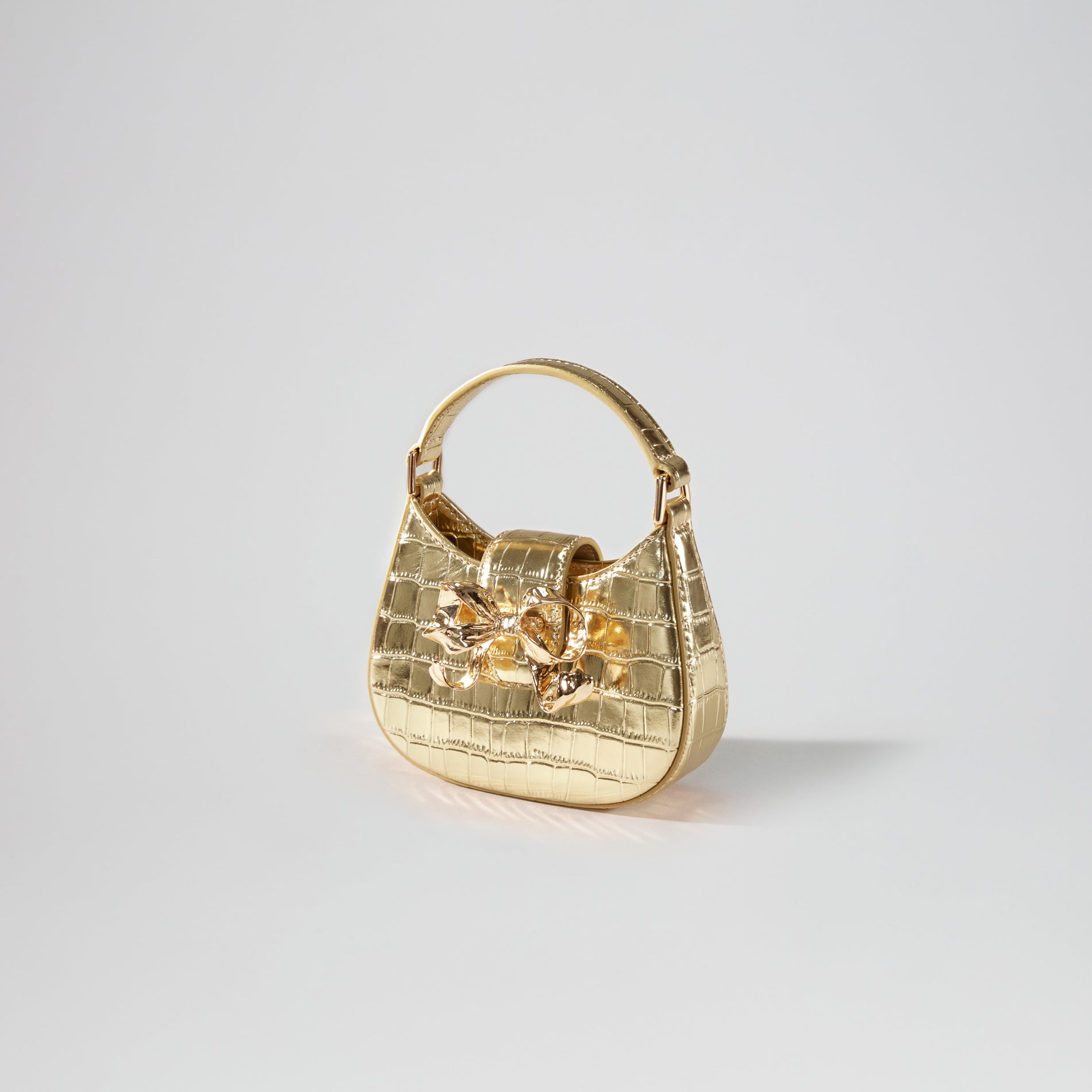 Side view of a woman wearing the Gold Croc Crescent Bow Micro Bag