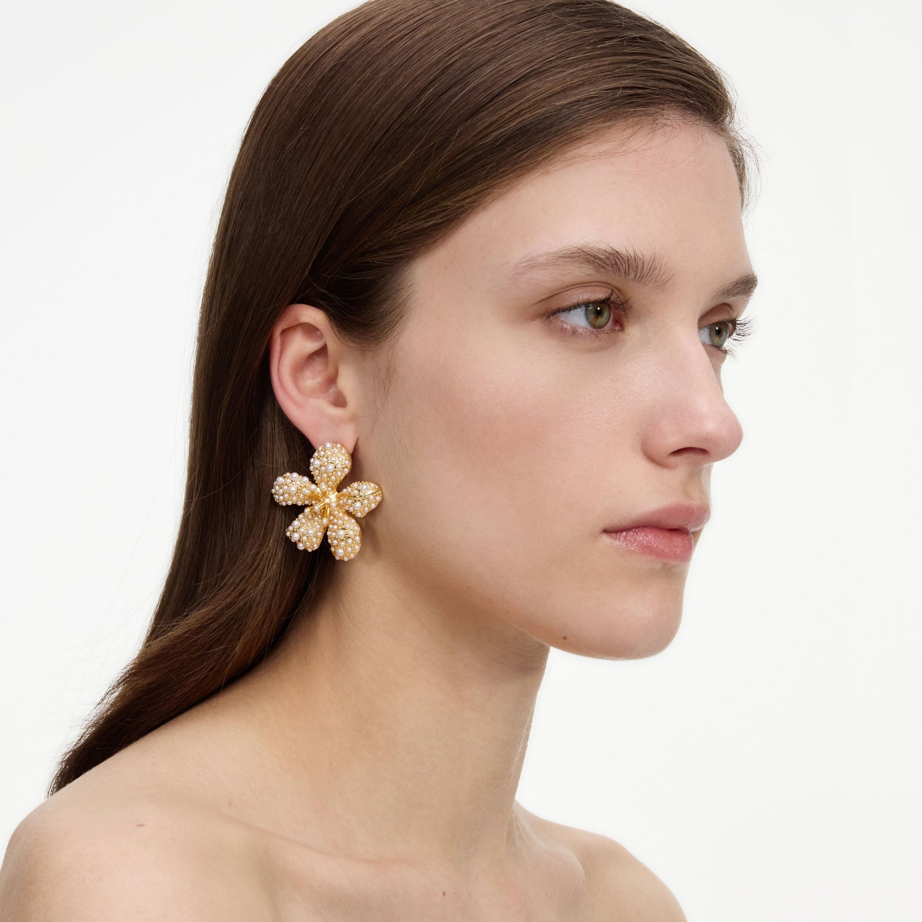 A close up of a woman wearing the Gold Pearl Encrusted Flower Earrings