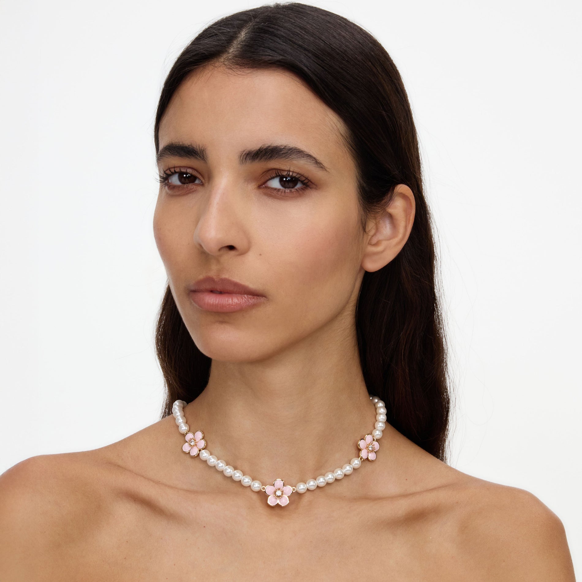 A close up of a woman wearing the Pink Enamel Flower Pearl Choker