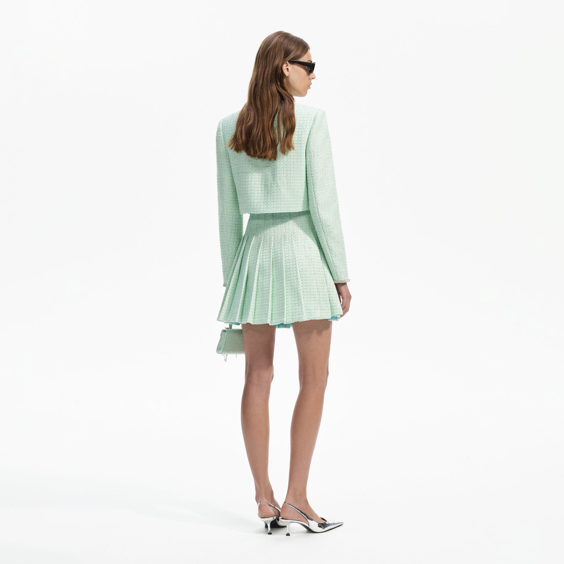 Back view of a woman wearing the Mint Boucle Pleated Mini Skirt