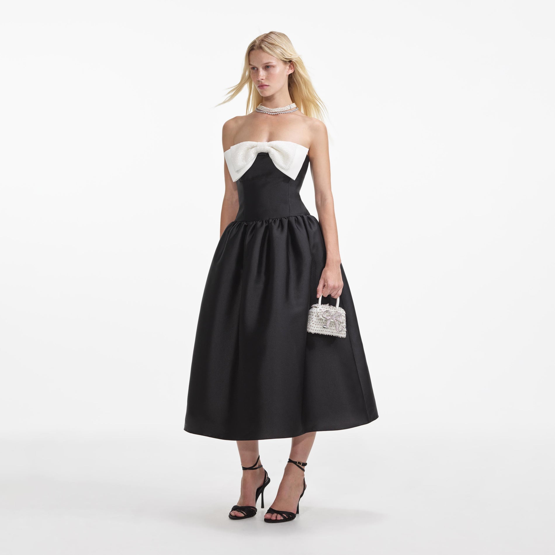 Side view of a woman wearing the Black Taffeta Contrast Bow Midi Dress