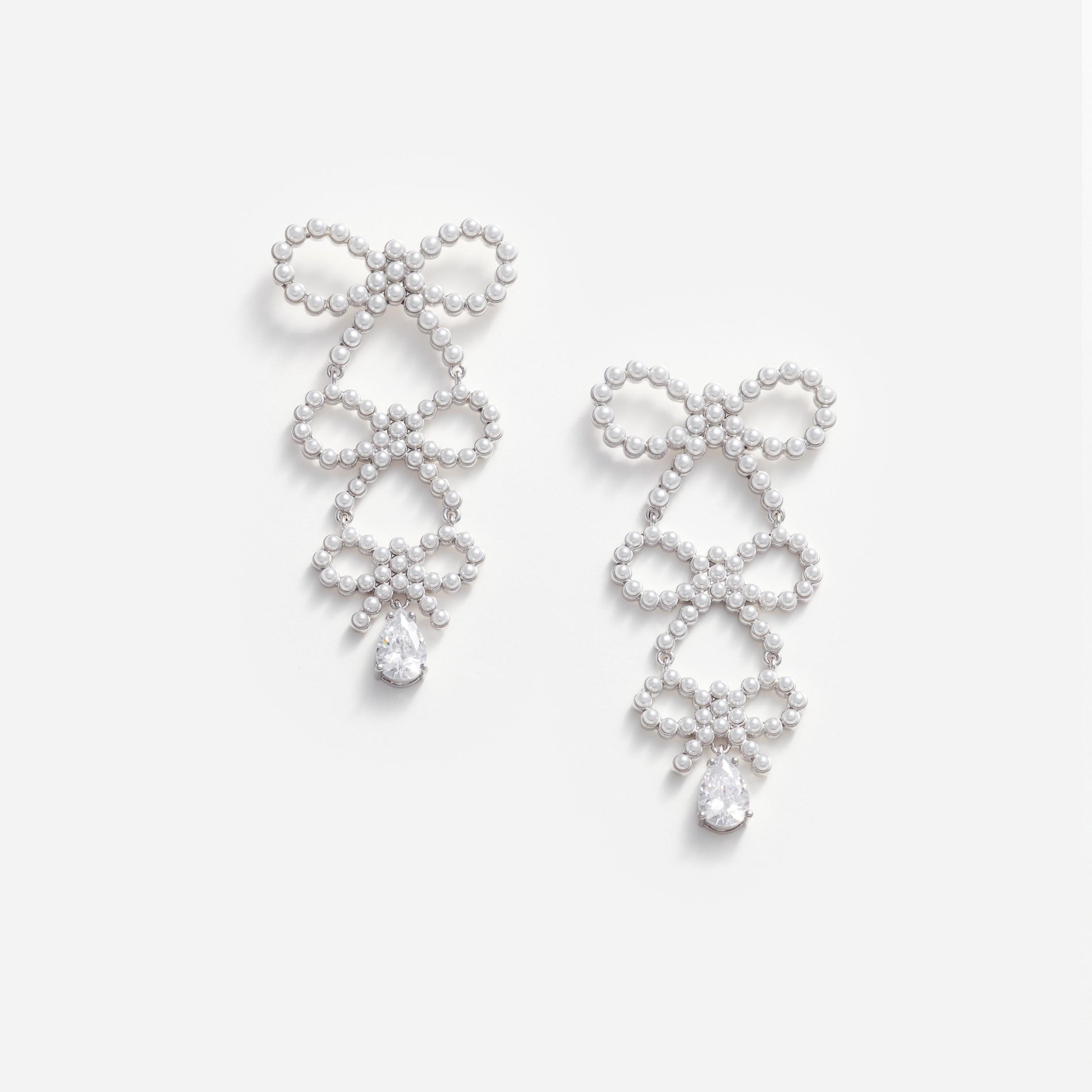 Front view of a woman wearing the Tiered Pearl Bow Earrings