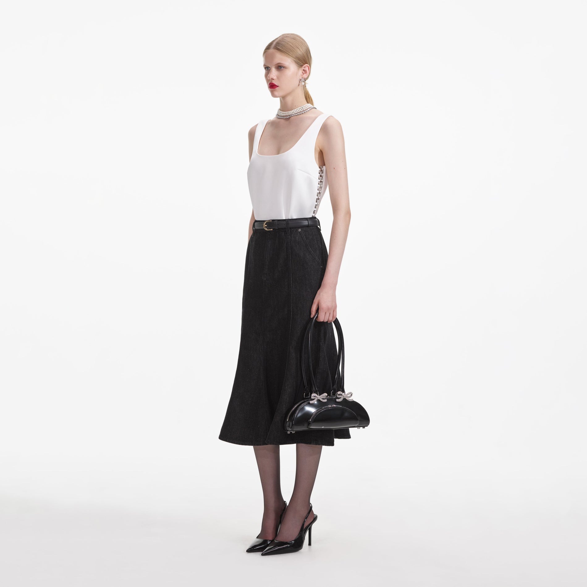 Side view of a woman wearing the Black Flared Denim Midi Skirt