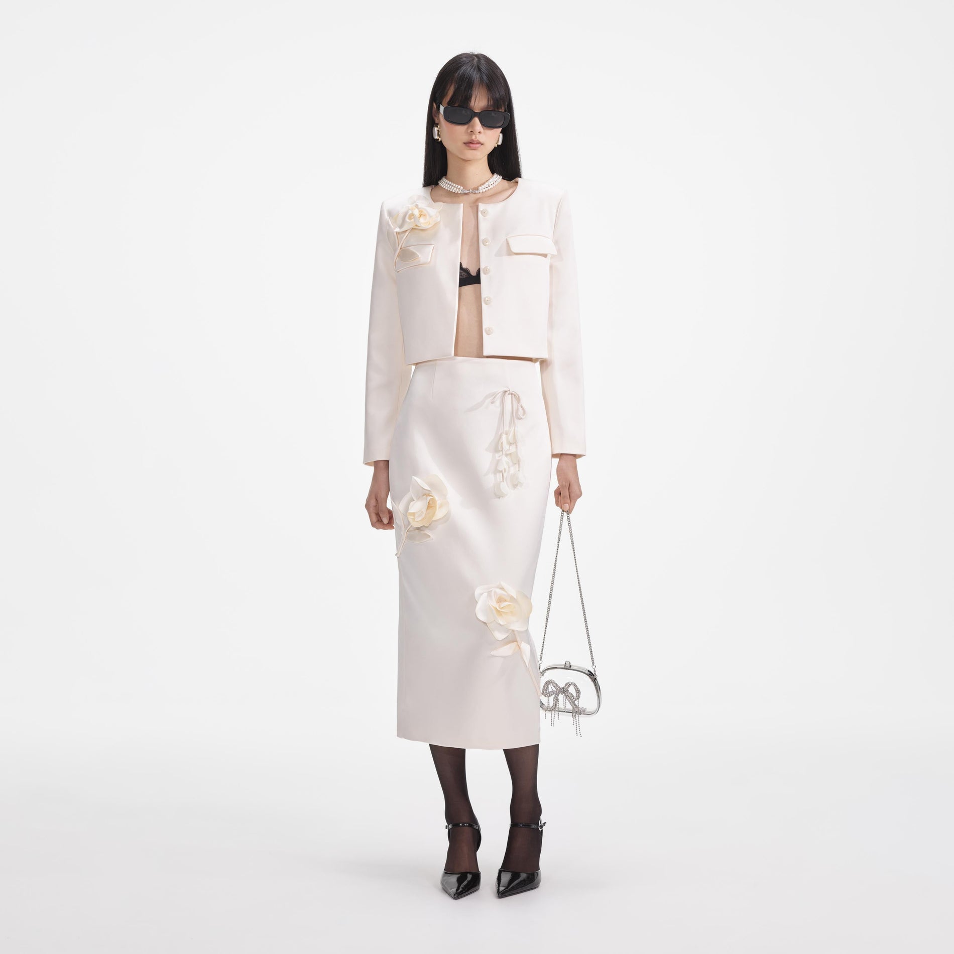 A close up of a woman wearing the Cream 3D Flower Satin Midi Skirt