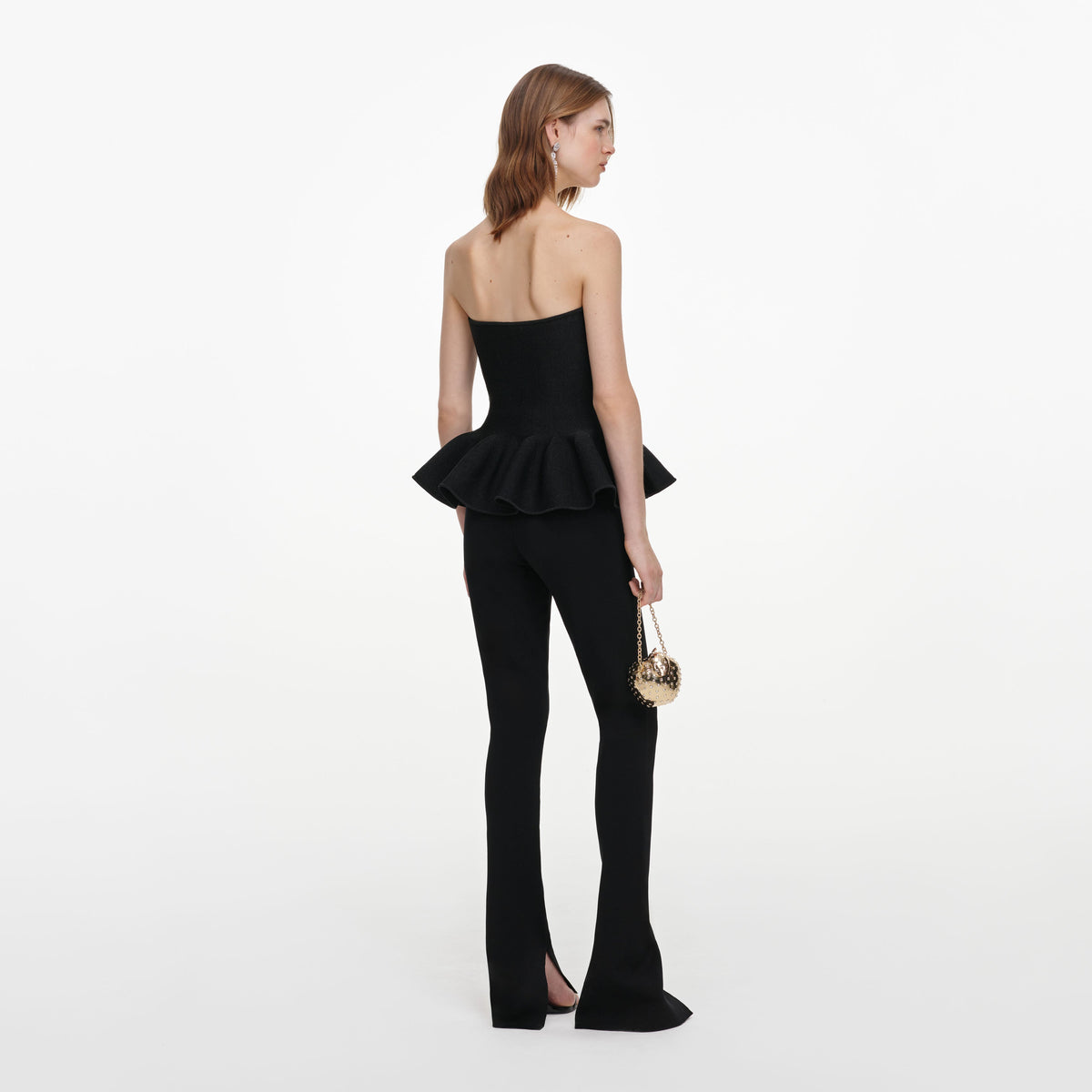 Back view of a woman wearing the Black Metallic Frill Peplum Knit Top