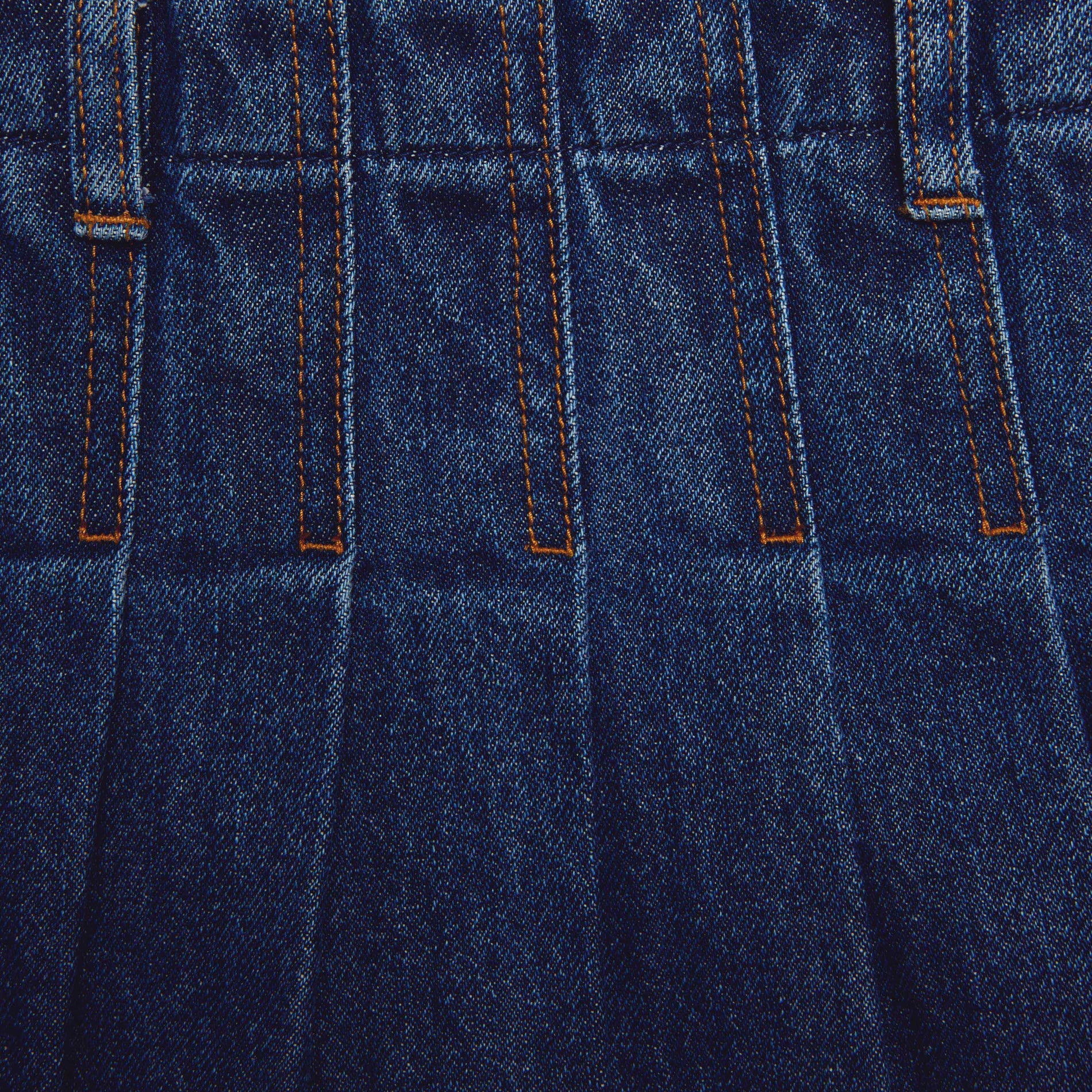 Side view of a woman wearing the Pleated Denim Midi Skirt