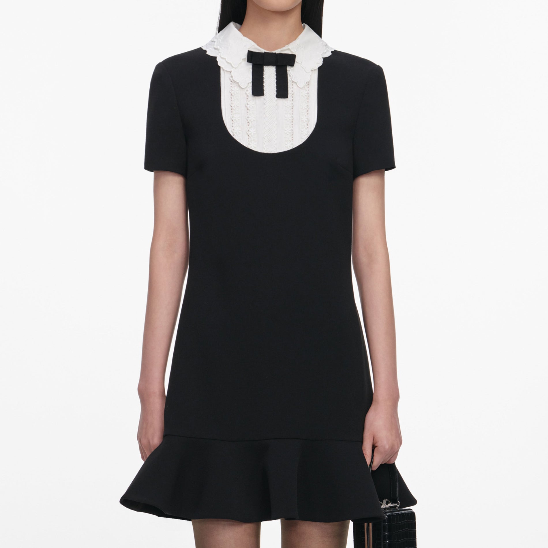 A close up of a woman wearing the Black Crepe Lace Bib Mini Dress