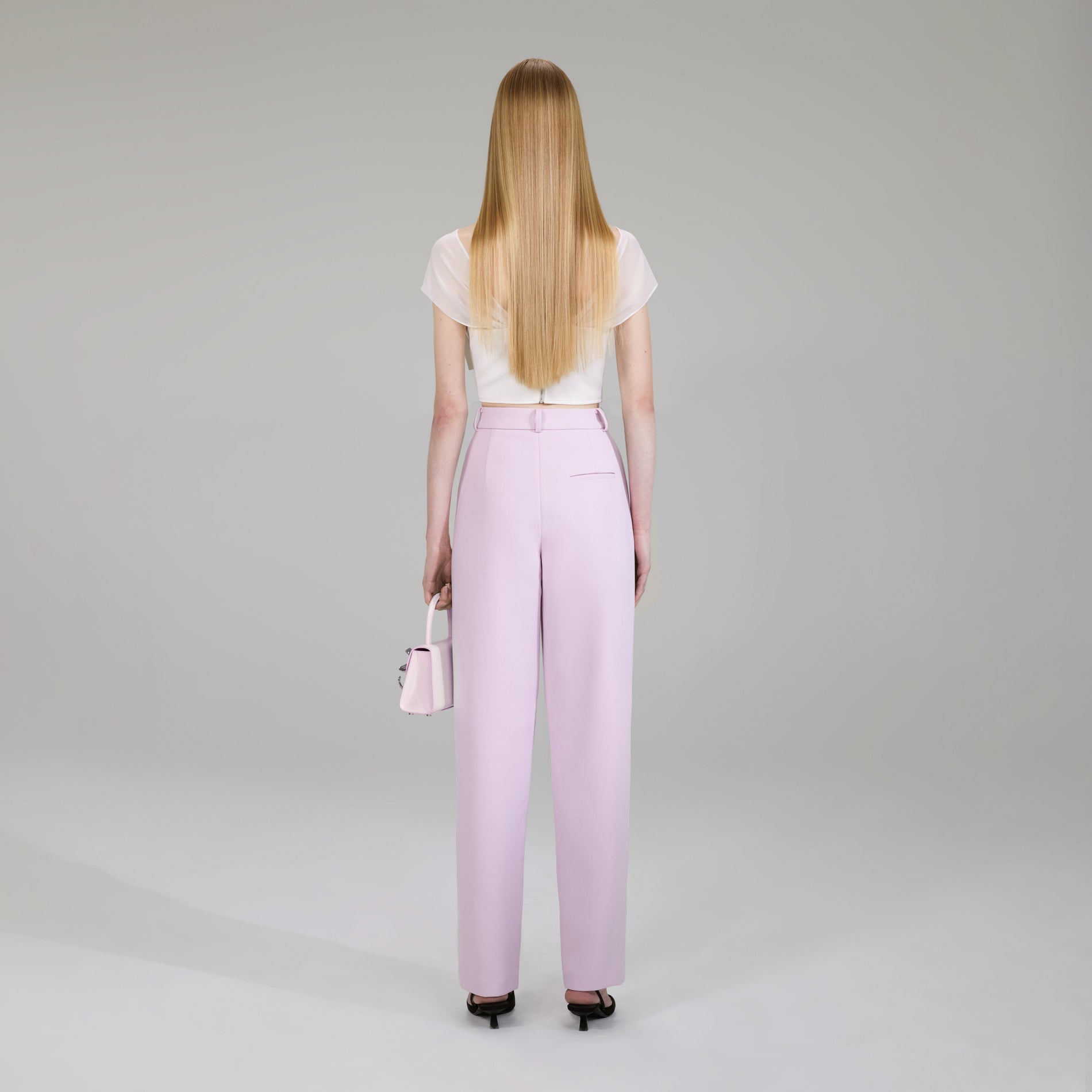 A woman wearing the Pink Crepe Trousers