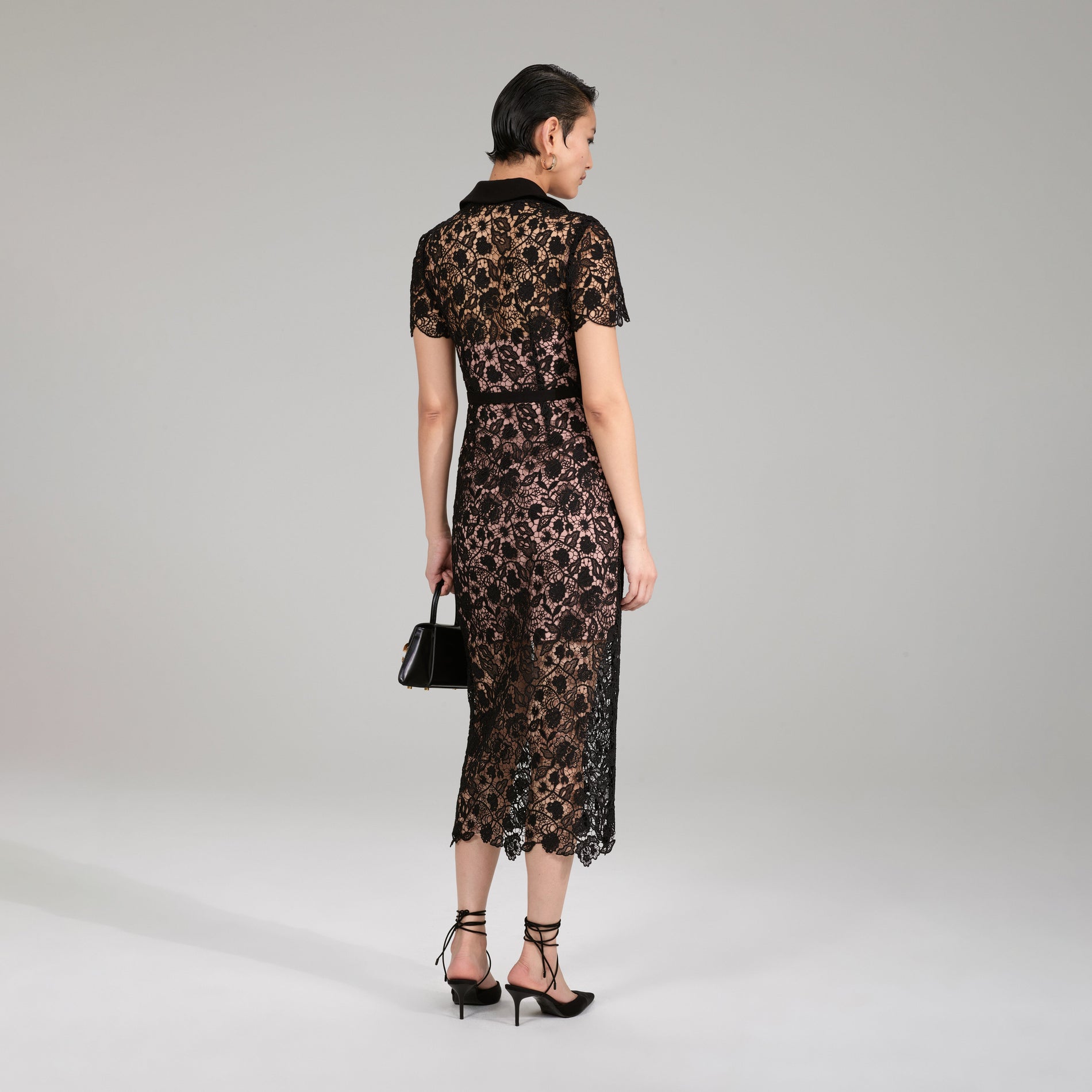 A woman wearing the Black Magnolia Lace Midi Dress