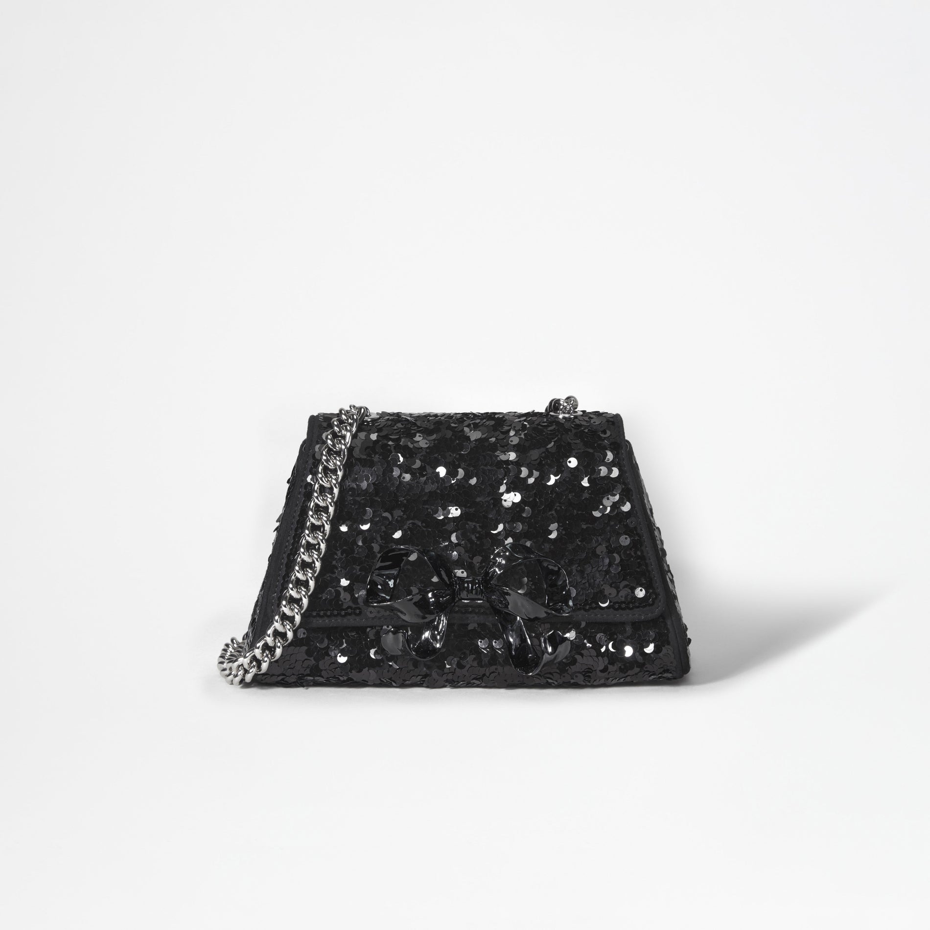 A woman wearing the Black Sequin Bow Mini Shoulder Bag