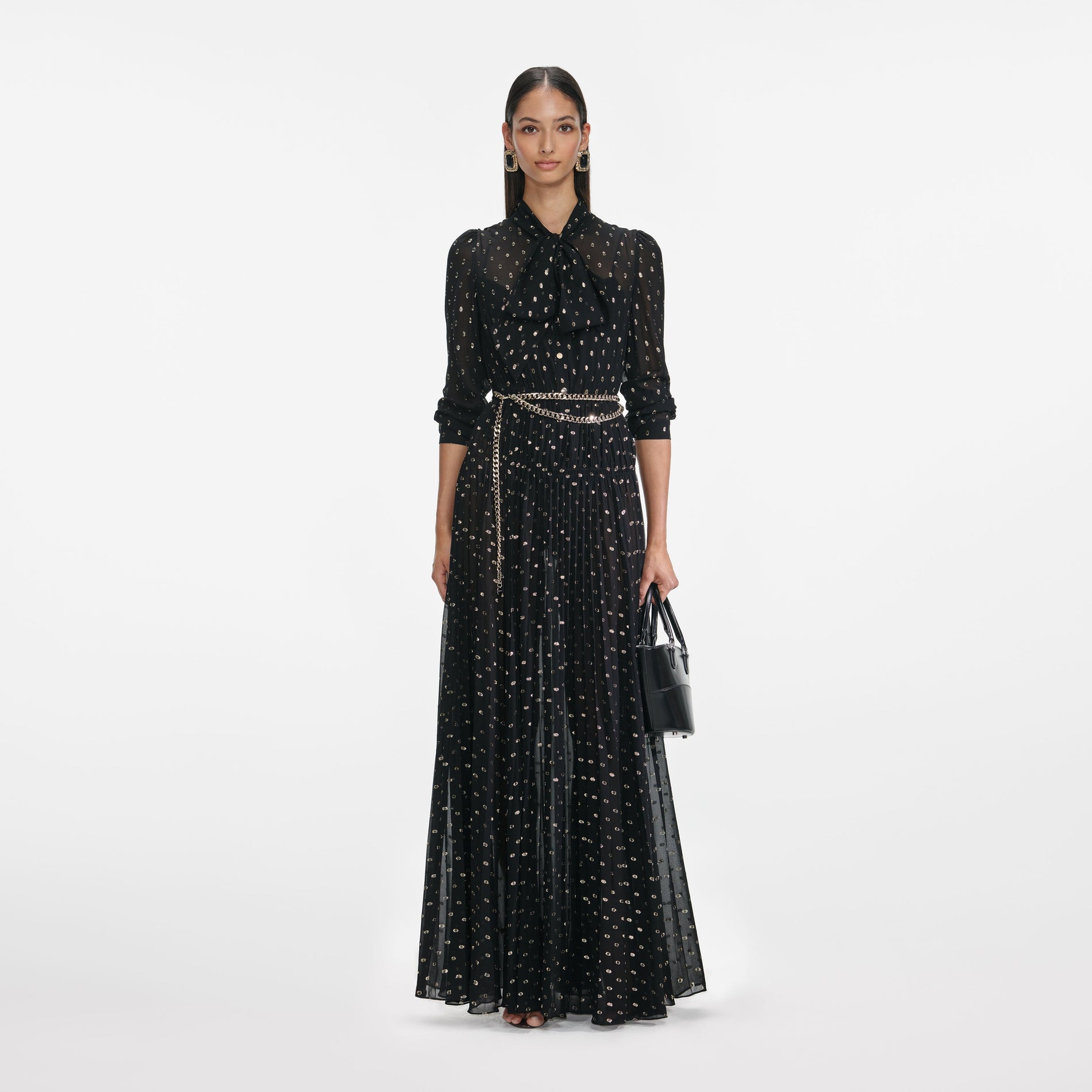 Front view of a woman wearing the Black And Gold Pussy Bow Maxi Dress