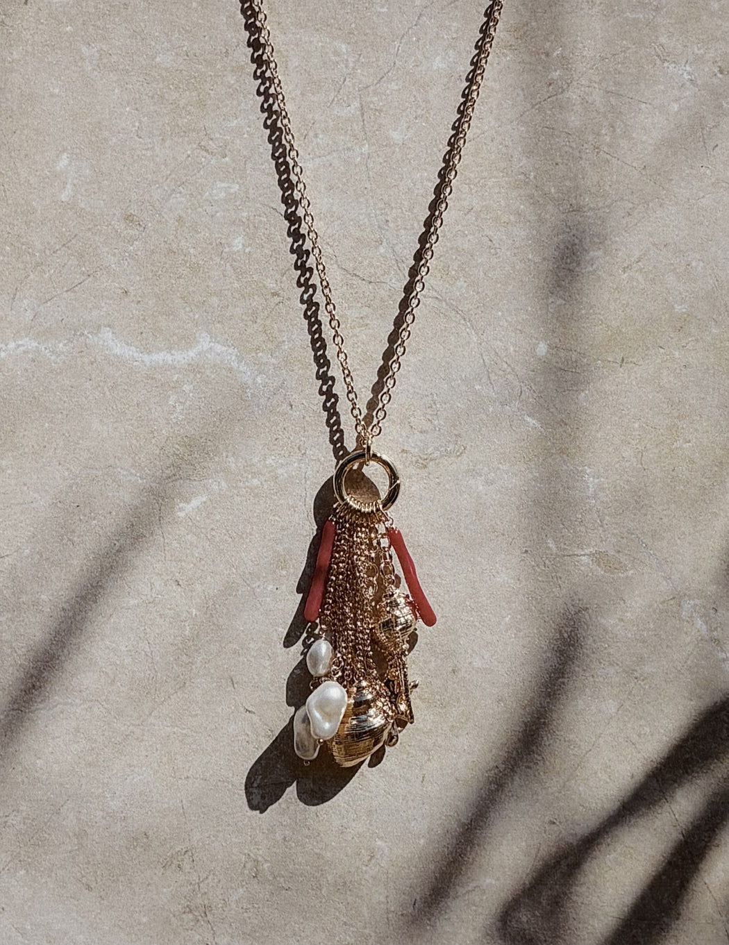 Gold chain necklace with a charm cluster featuring pearls, gold beads, and red coral pieces