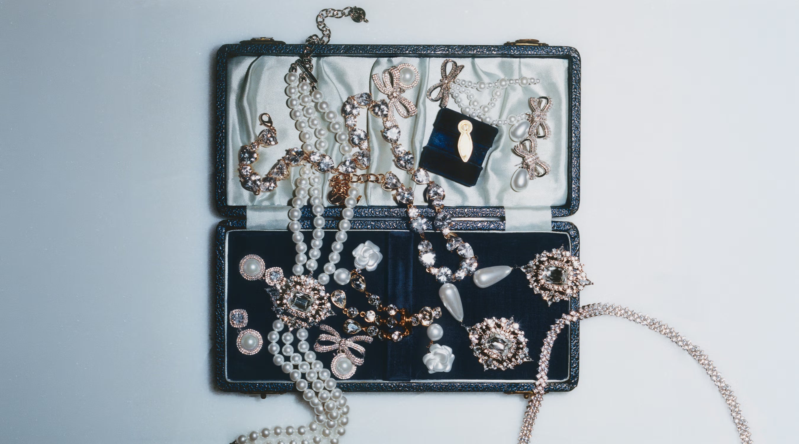 Jewellery set with necklaces and earrings displayed on an open jewellery box against a light grey background.