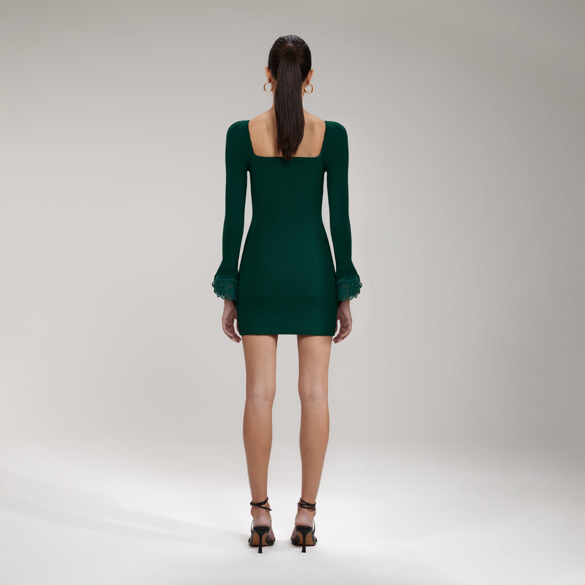 A woman wearing the Dark Green Inserted Lace Ribbed Knit Mini Dress