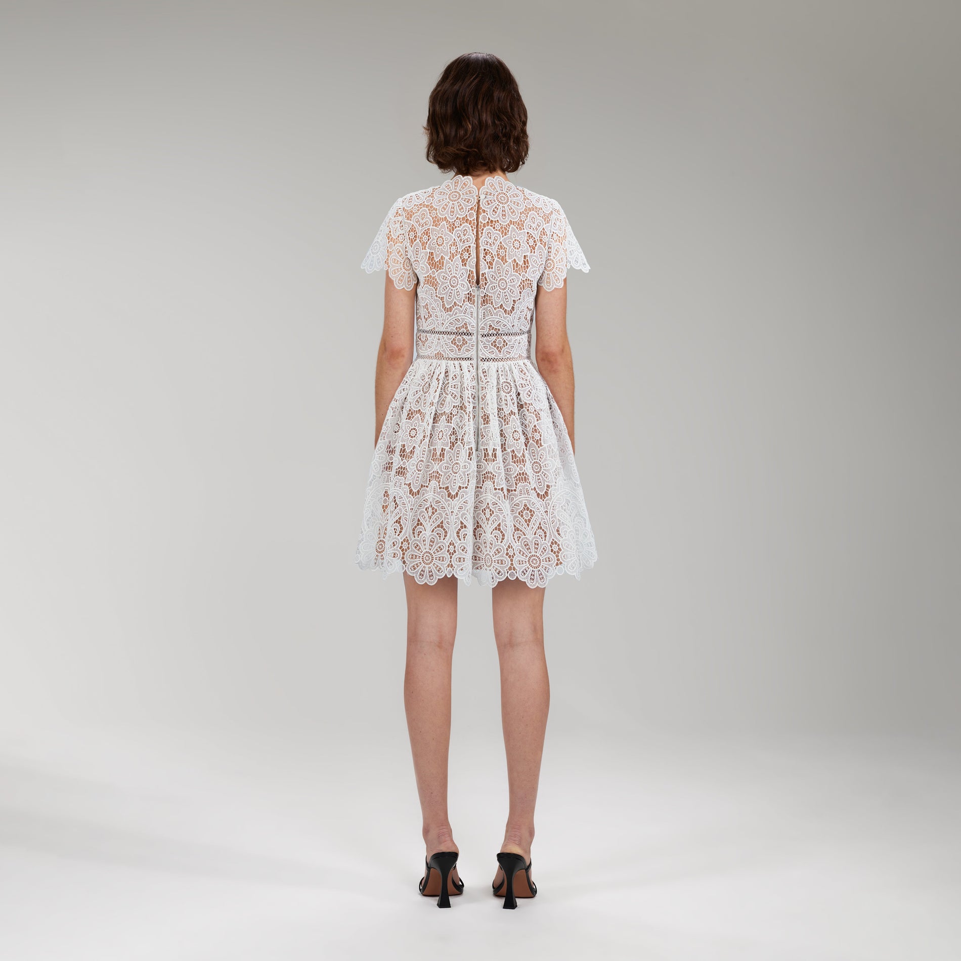 A woman wearing the White Floral Guipure Lace Mini Dress