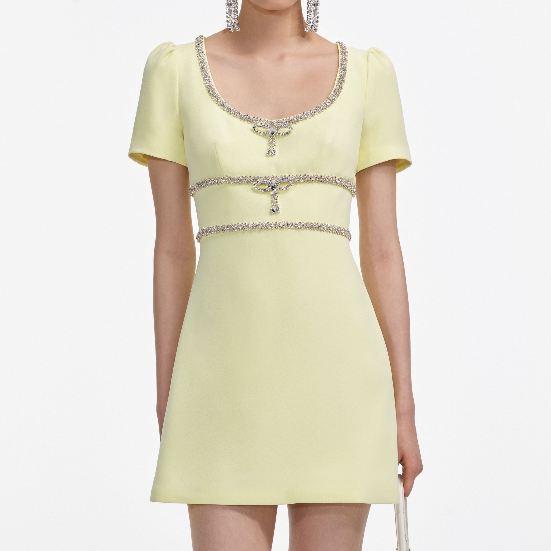 A close up of a woman wearing the Yellow Crepe Crystal Trim Mini Dress