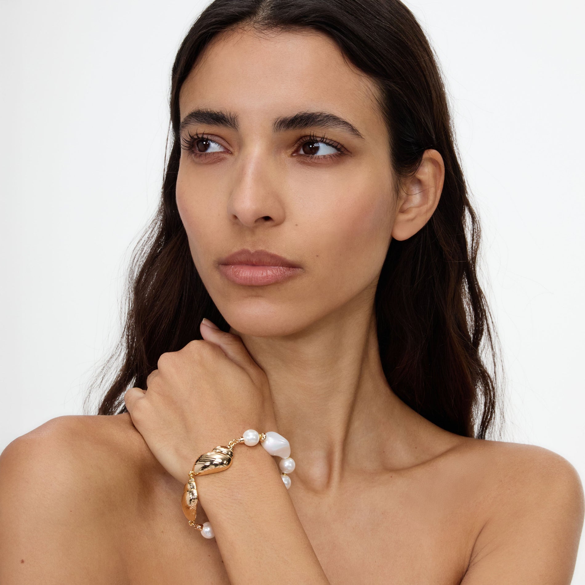 A close up of a woman wearing the Gold Shell And Pearl Bracelet