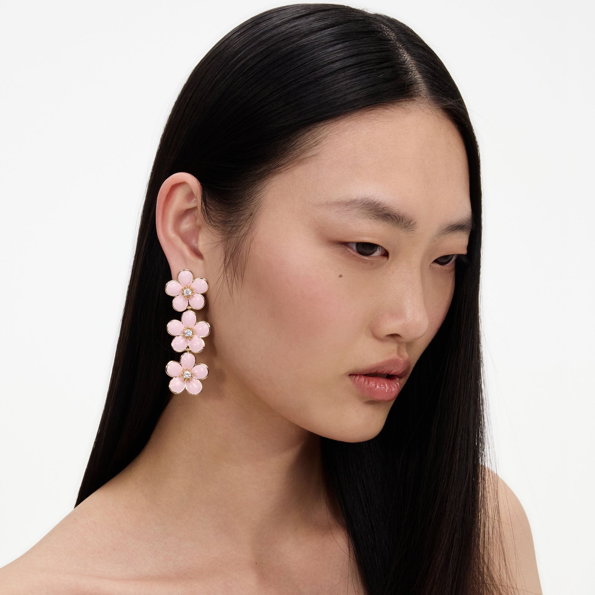 A close up of a woman wearing the Pink Enamel Flower Tiered Earrings