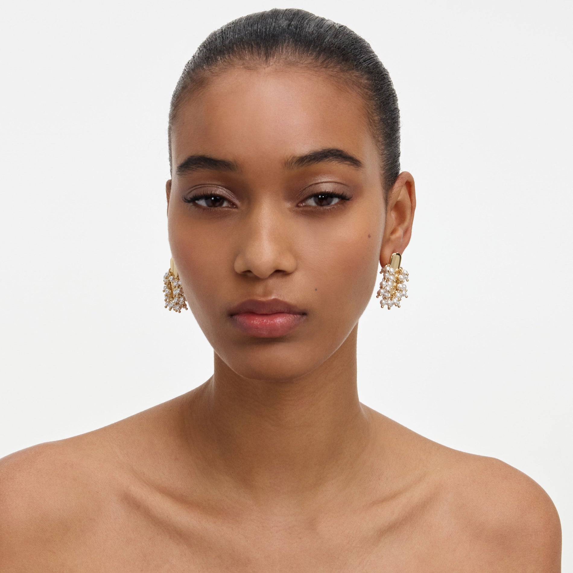 A close up of a woman wearing the Gold Pearl Cluster Earrings