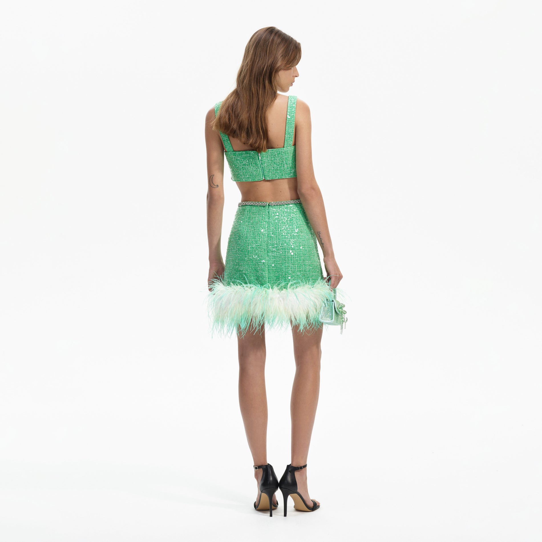 Back view of a woman wearing the Green Boucle Feather Mini Skirt