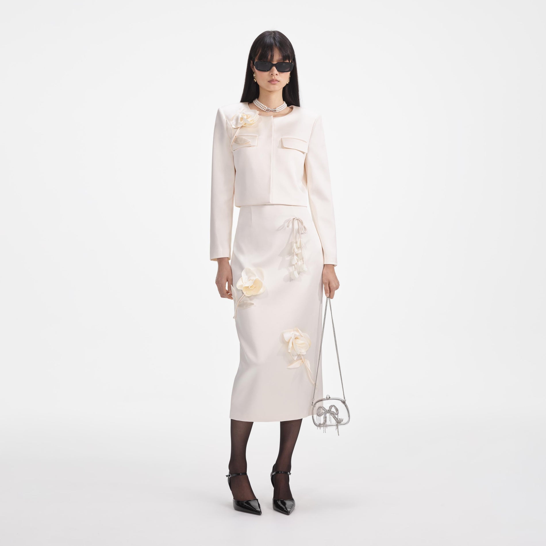 Front view of a woman wearing the Cream 3D Flower Satin Midi Skirt