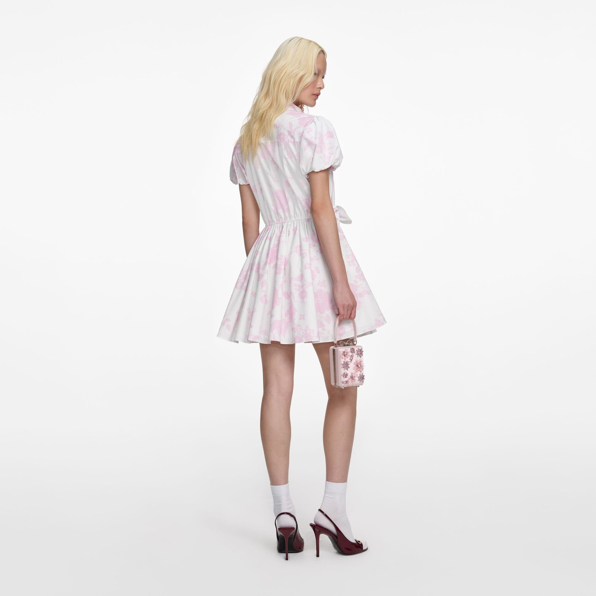 Back view of a woman wearing the Pink Floral Cotton Drape Mini Dress