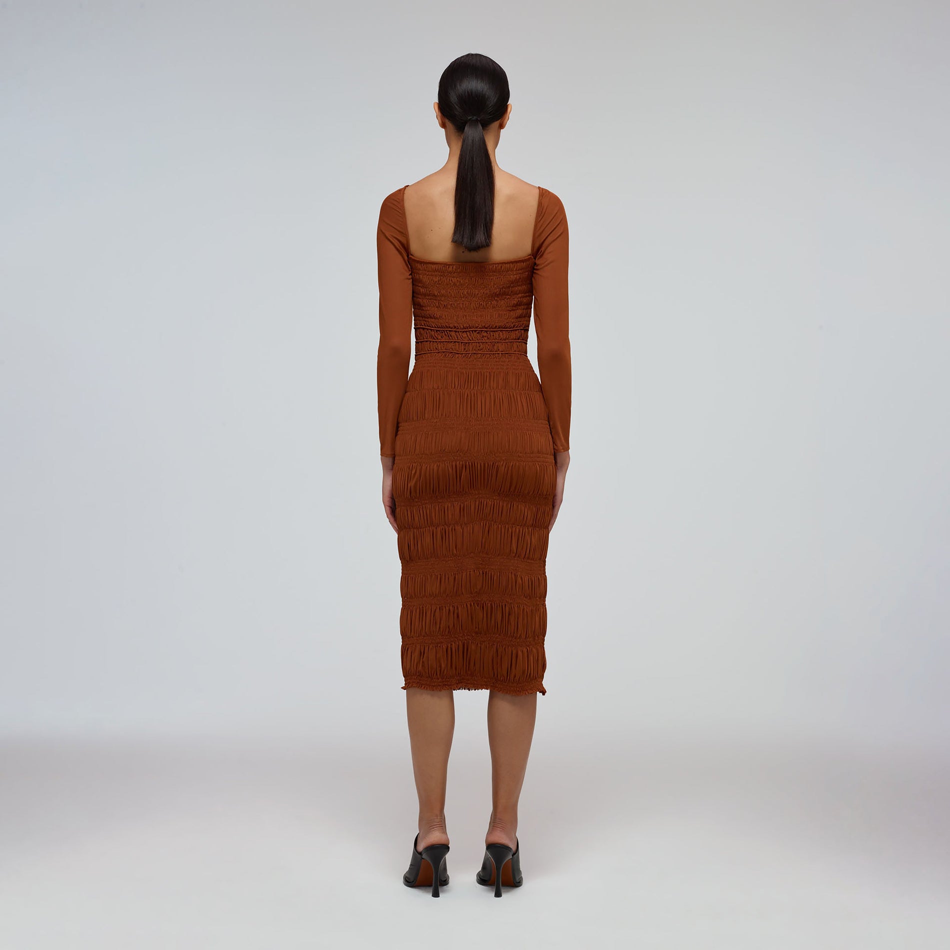 A woman wearing the Caramel Shirred Power Mesh Midi Dress