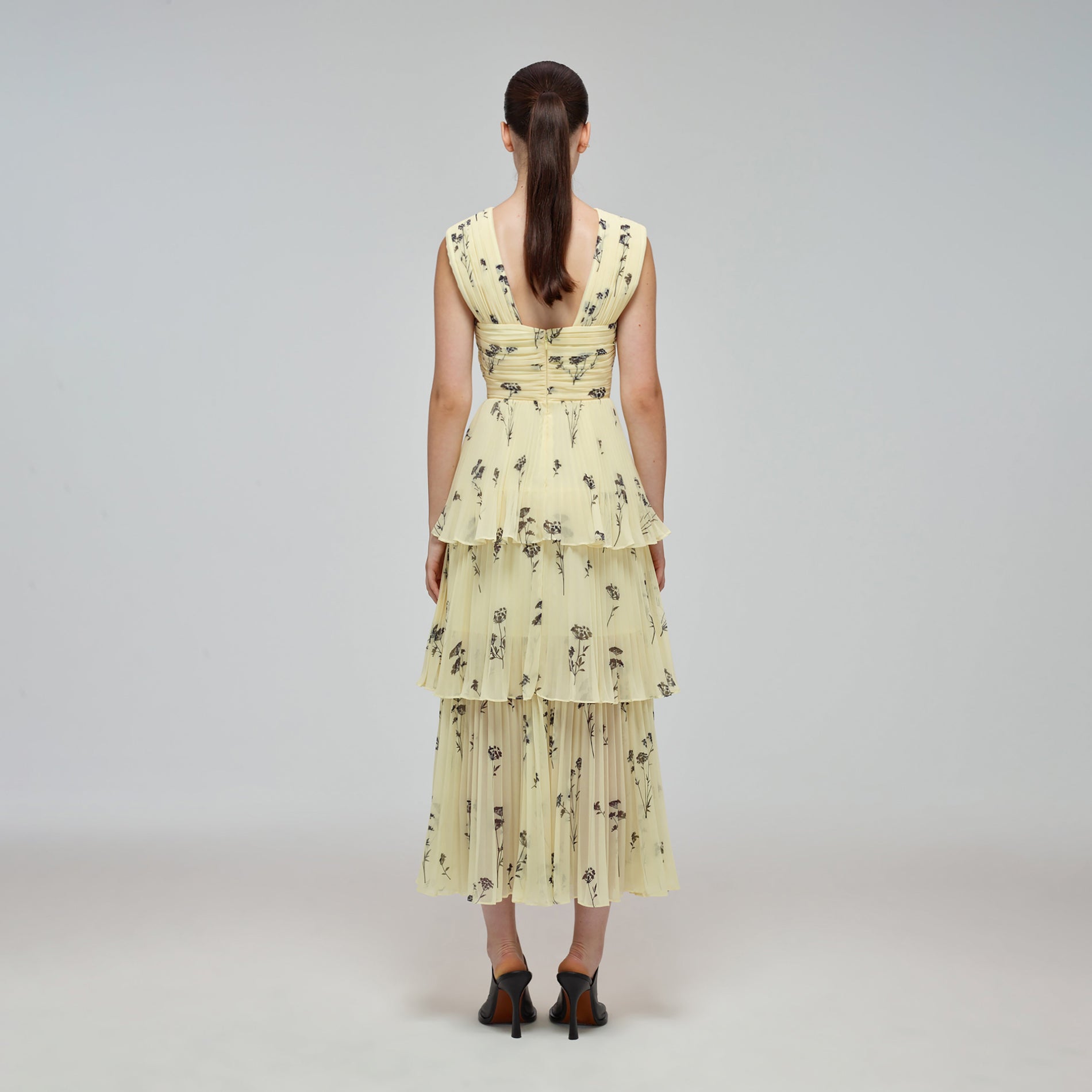 A woman wearing the Yellow Floral Silhouette Chiffon Crossover Midi Dress