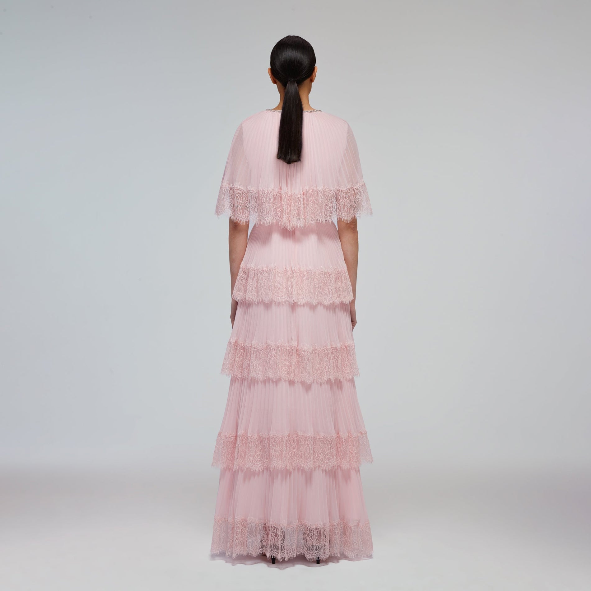 A woman wearing the Pink Tiered Chiffon Cape Maxi Dress