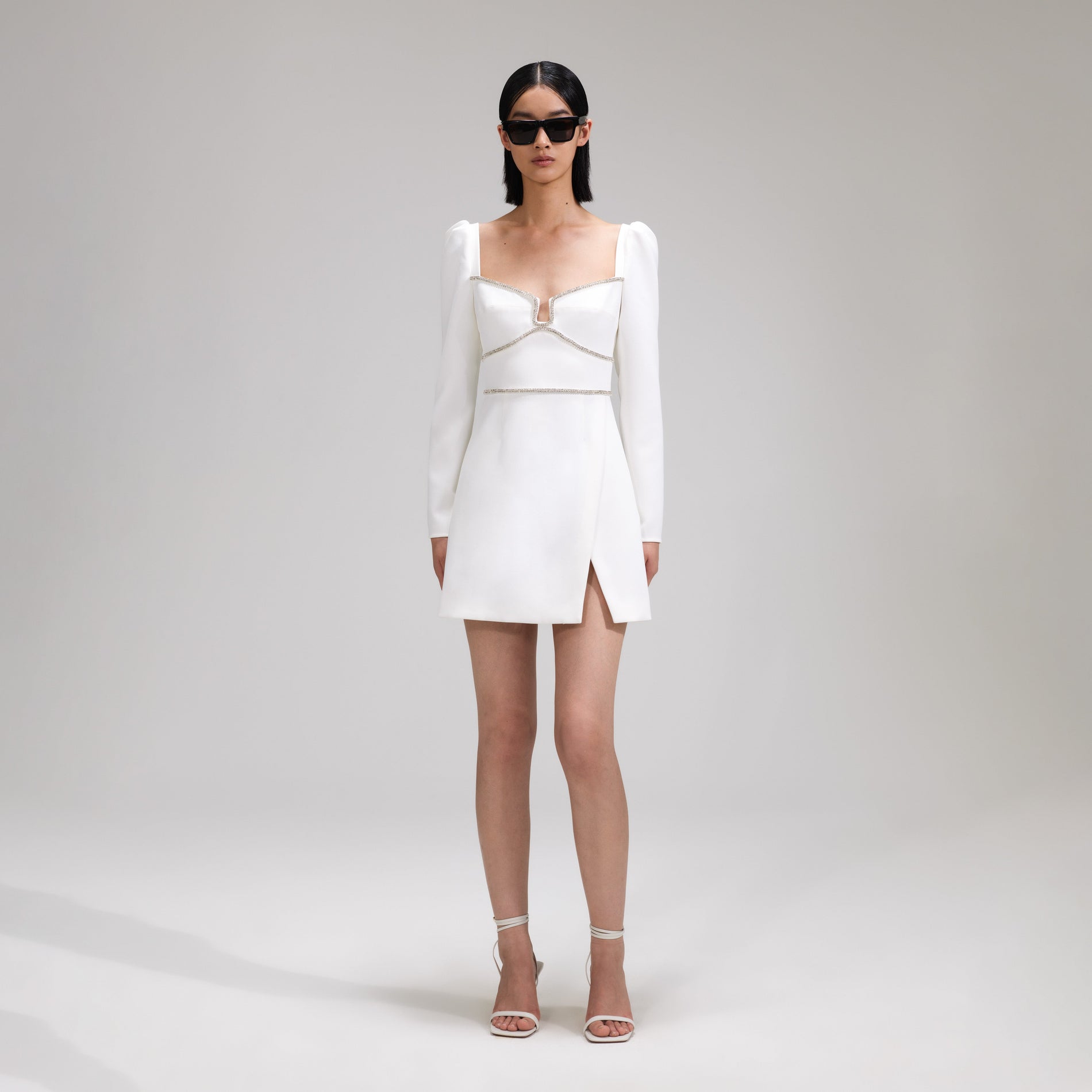 A woman wearing the White Crepe Rhinestone Detail Mini Dress