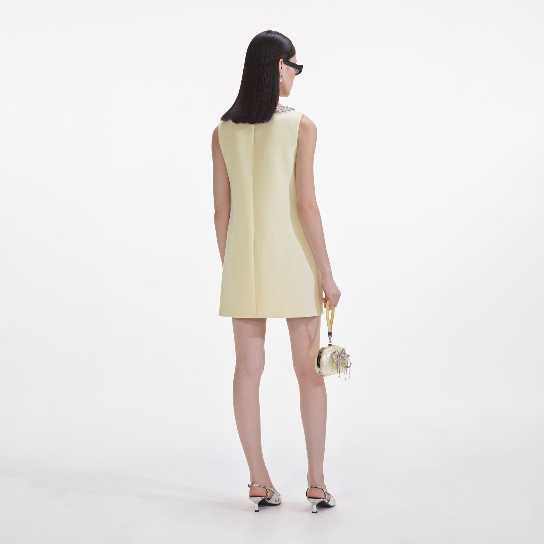 Back view of a woman wearing the Yellow Crepe Bow Mini Dress