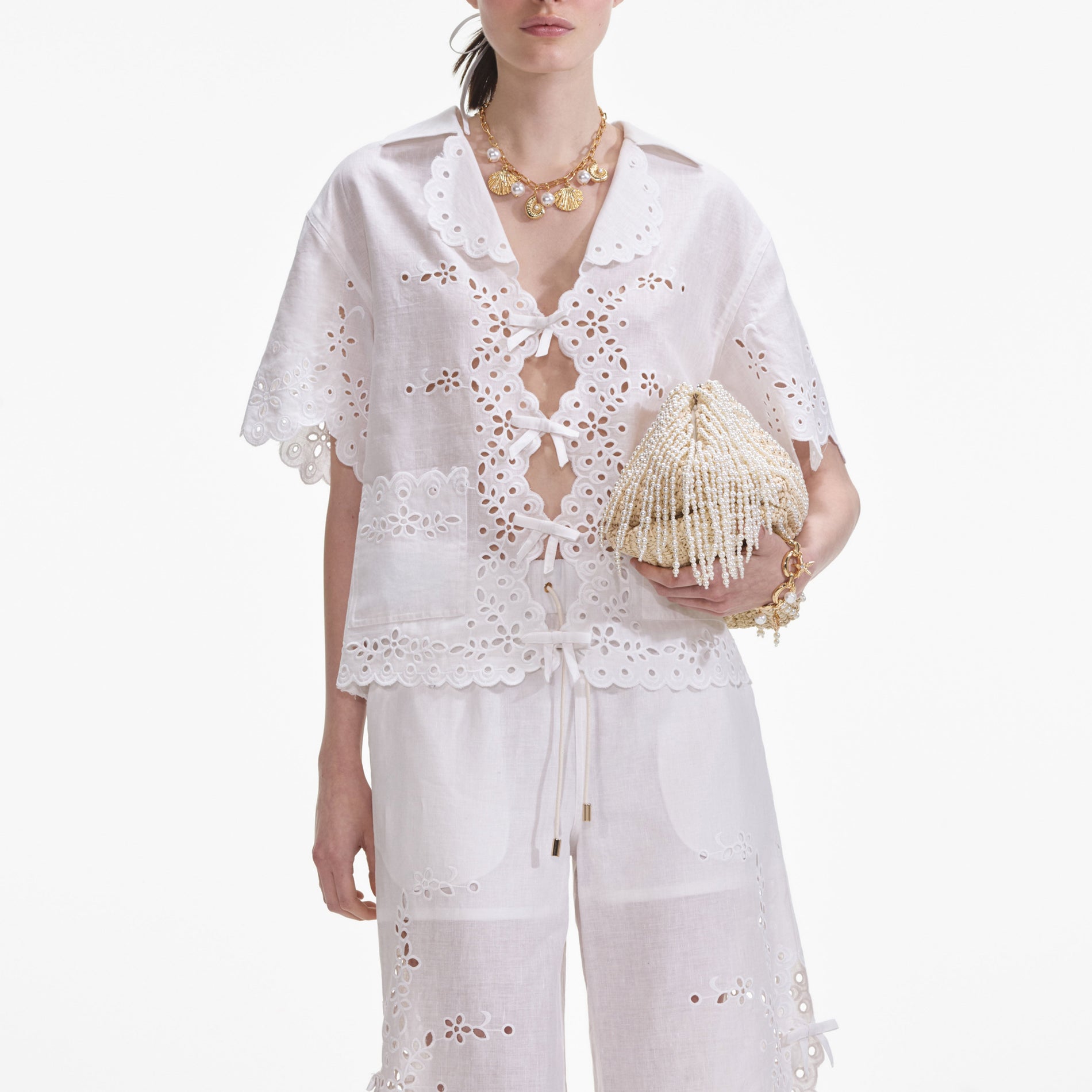 A close up of a woman wearing the Cream Linen Embroidered Trousers