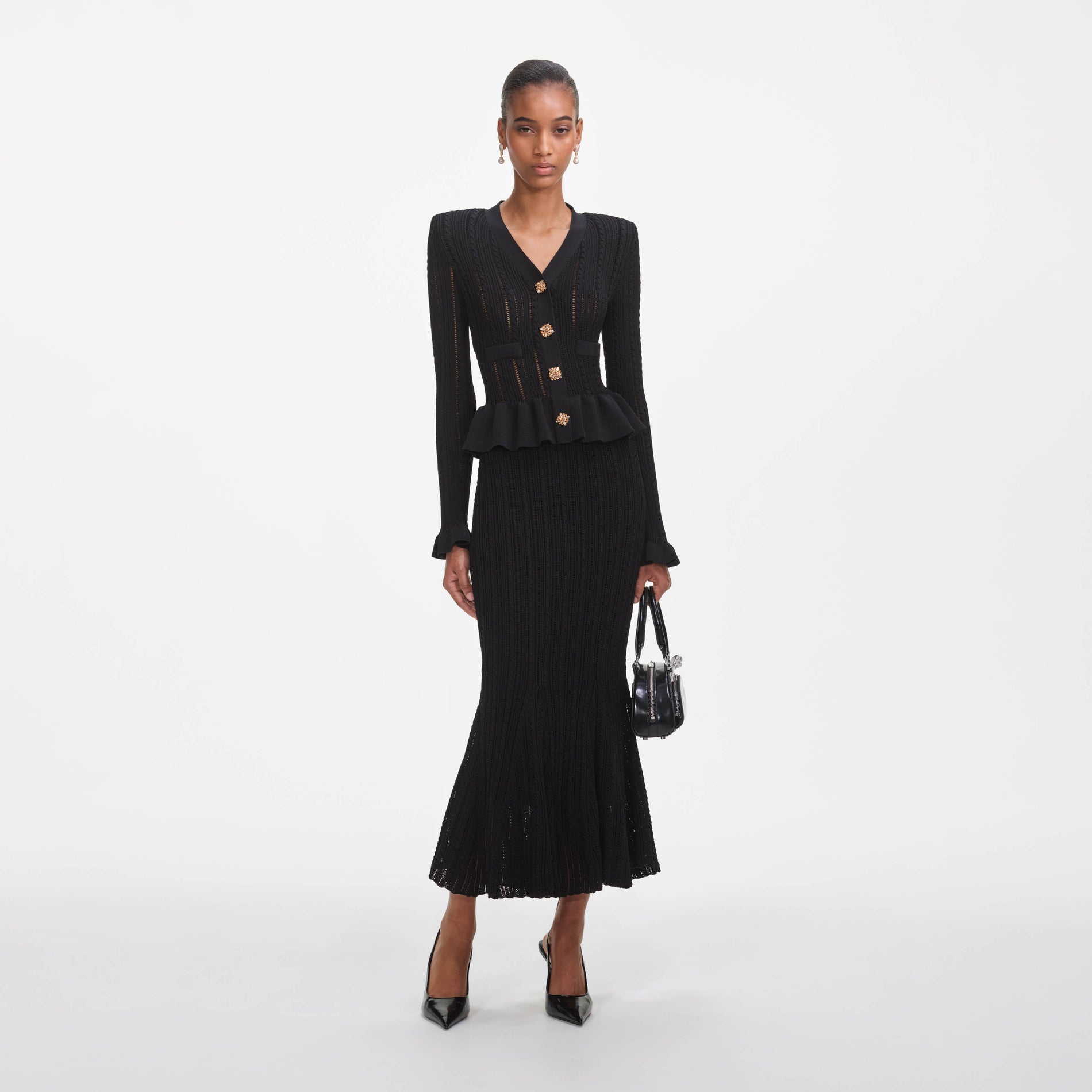 A close up of a woman wearing the Black Knit Peplum Midi Dress