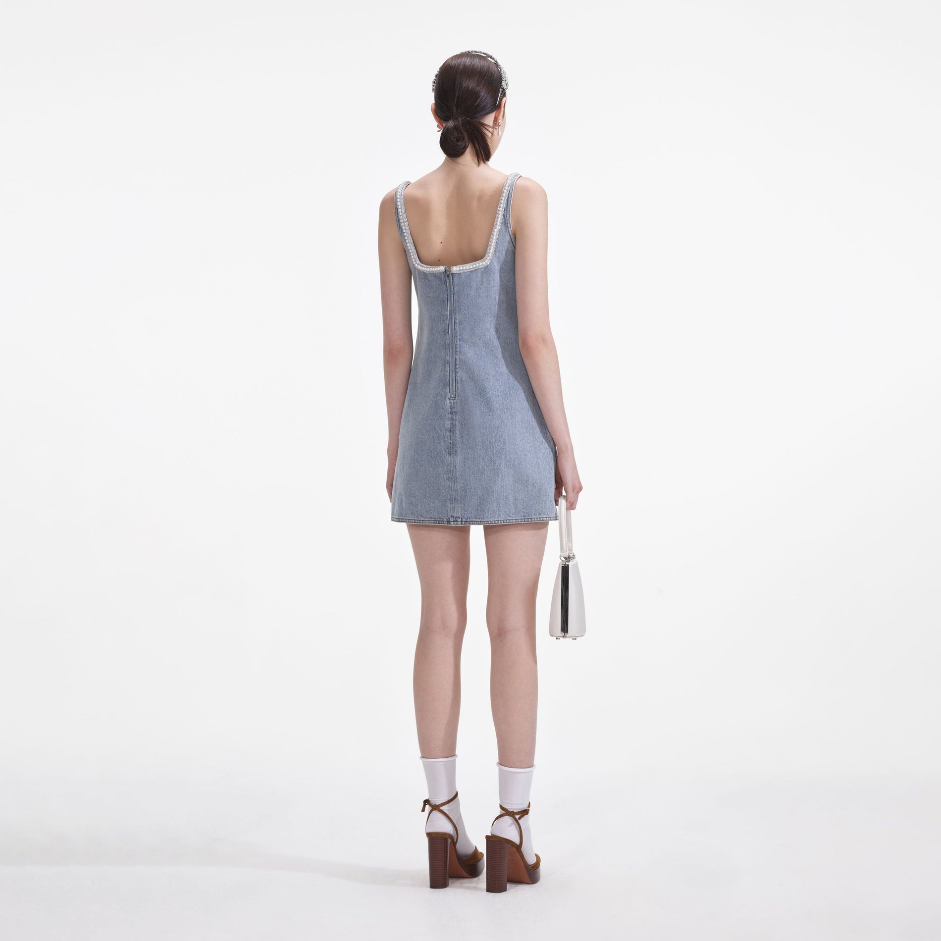 Back view of a woman wearing the Light Blue Denim Bow Mini Dress