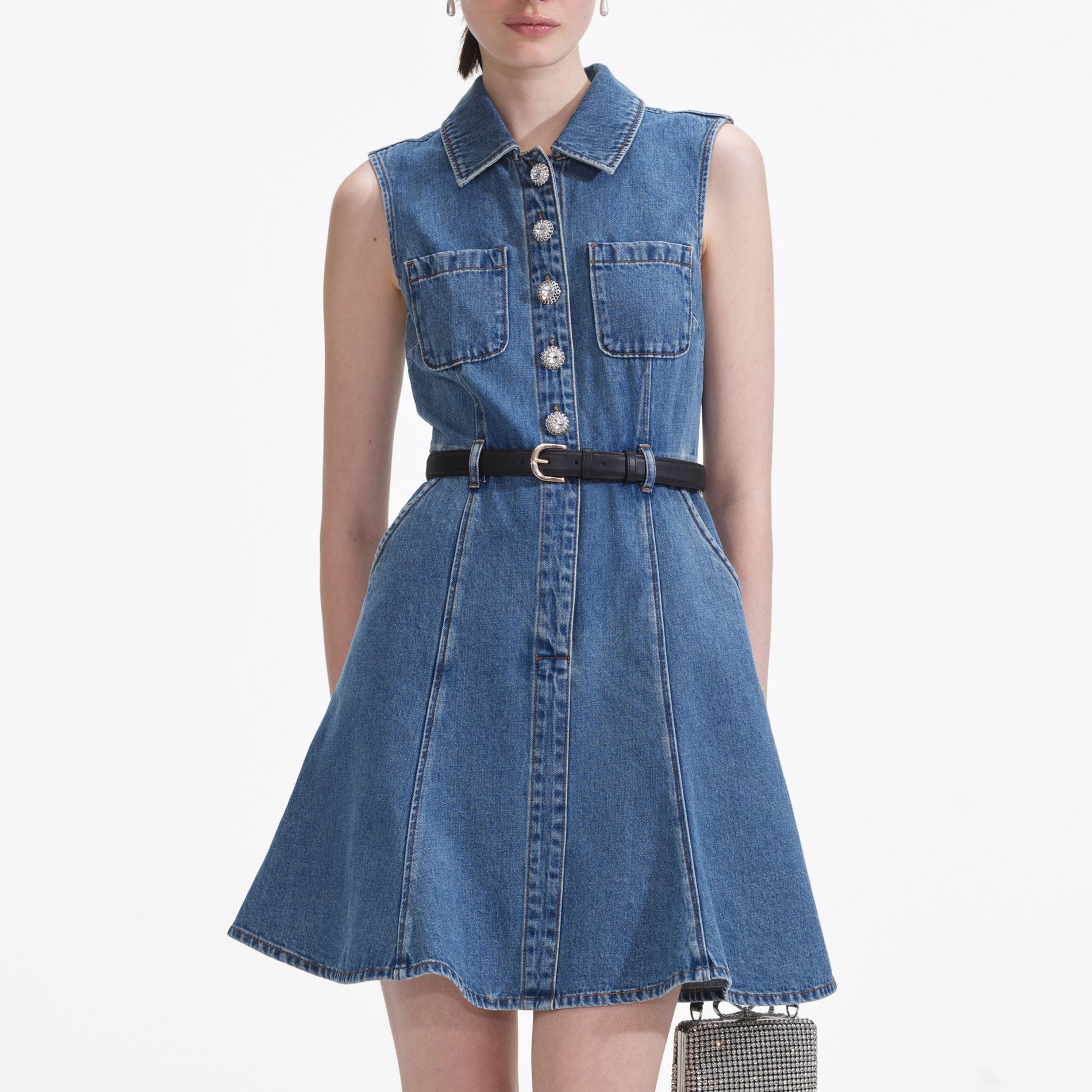 A close up of a woman wearing the Denim Sleeveless Pearl Mini Dress