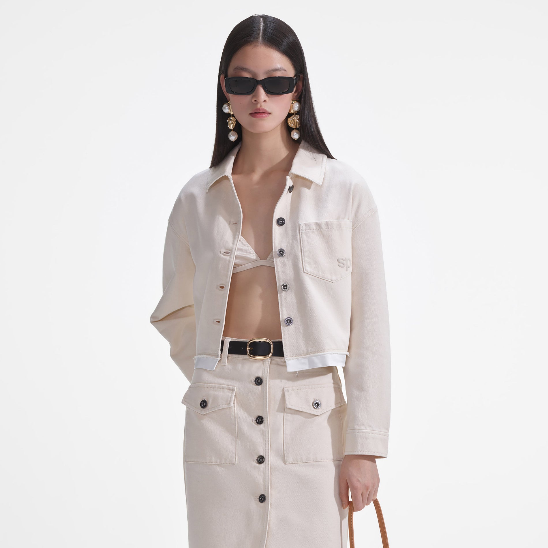 A close up of a woman wearing the Cream Denim Midi Skirt