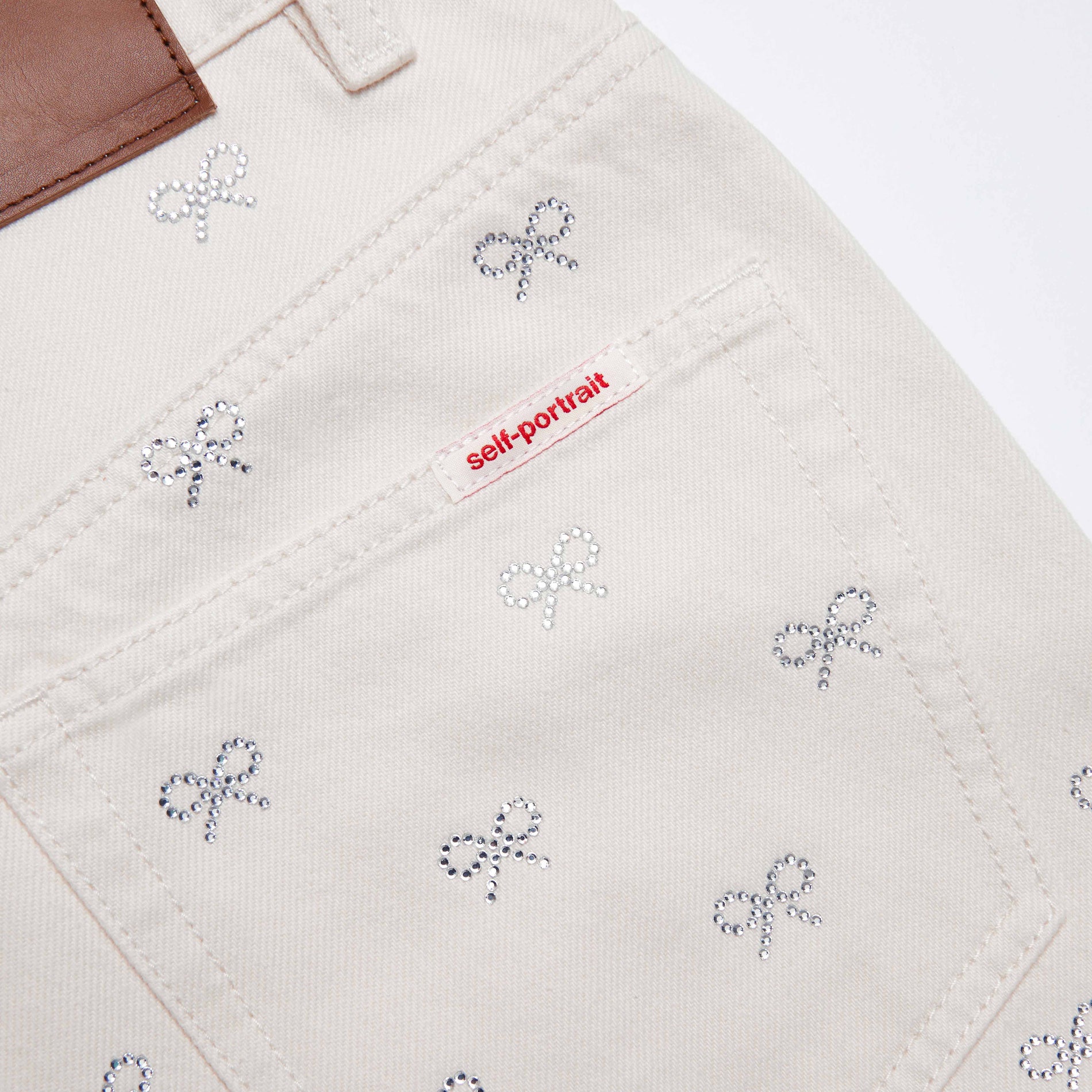 Side view of a woman wearing the Cream Denim Diamante Bow Jeans