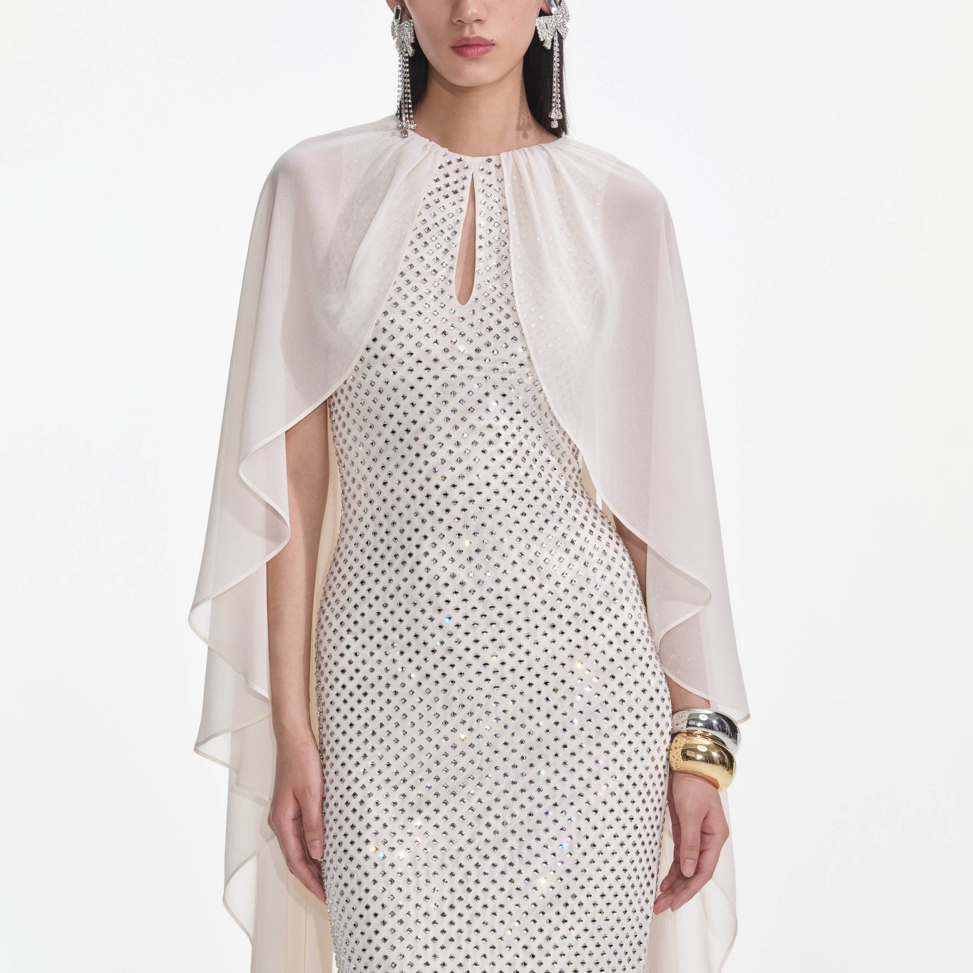 A close up of a woman wearing the Cream Rhinestone Cape Maxi Dress