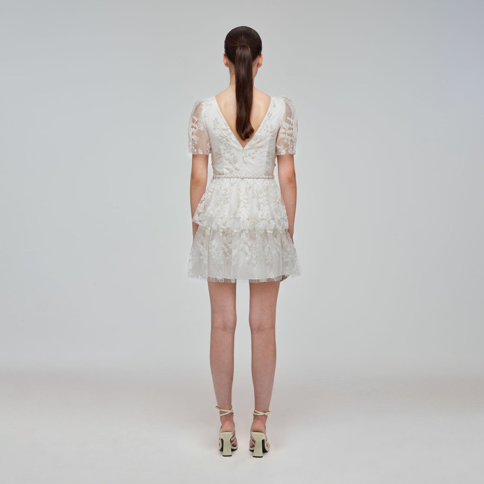 A woman wearing the Ivory Blossom Sequin Two Tier Mini Dress