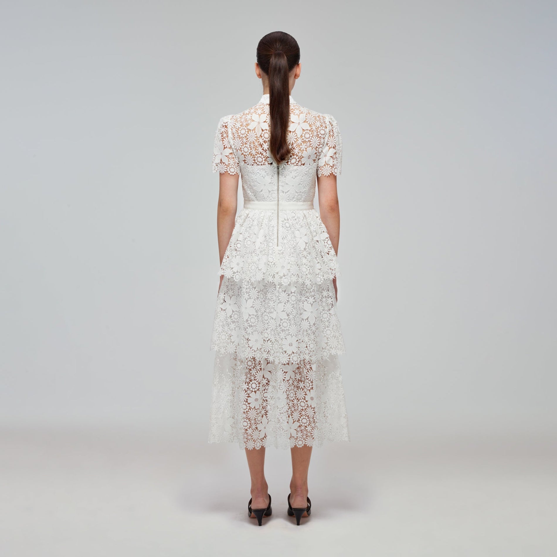 A woman wearing the White Guipure Lace Tiered Midi Dress