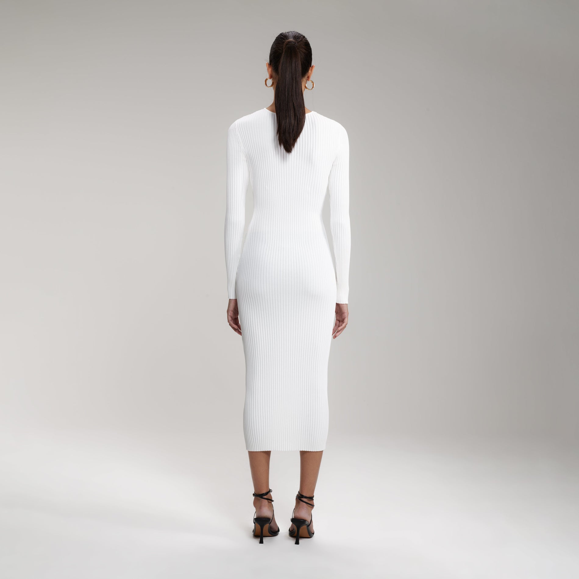 A woman wearing the White Ribbed Knit Cut Out Midi Dress