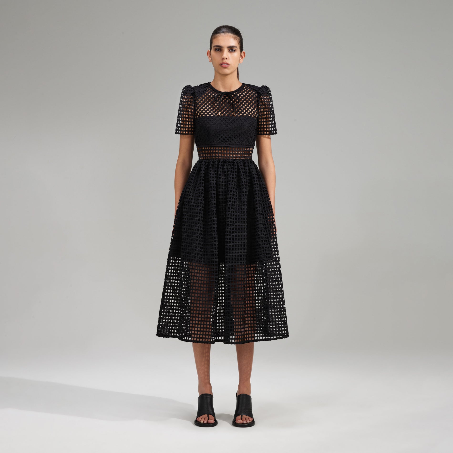 A woman wearing the Black Grid Lace Midi Dress