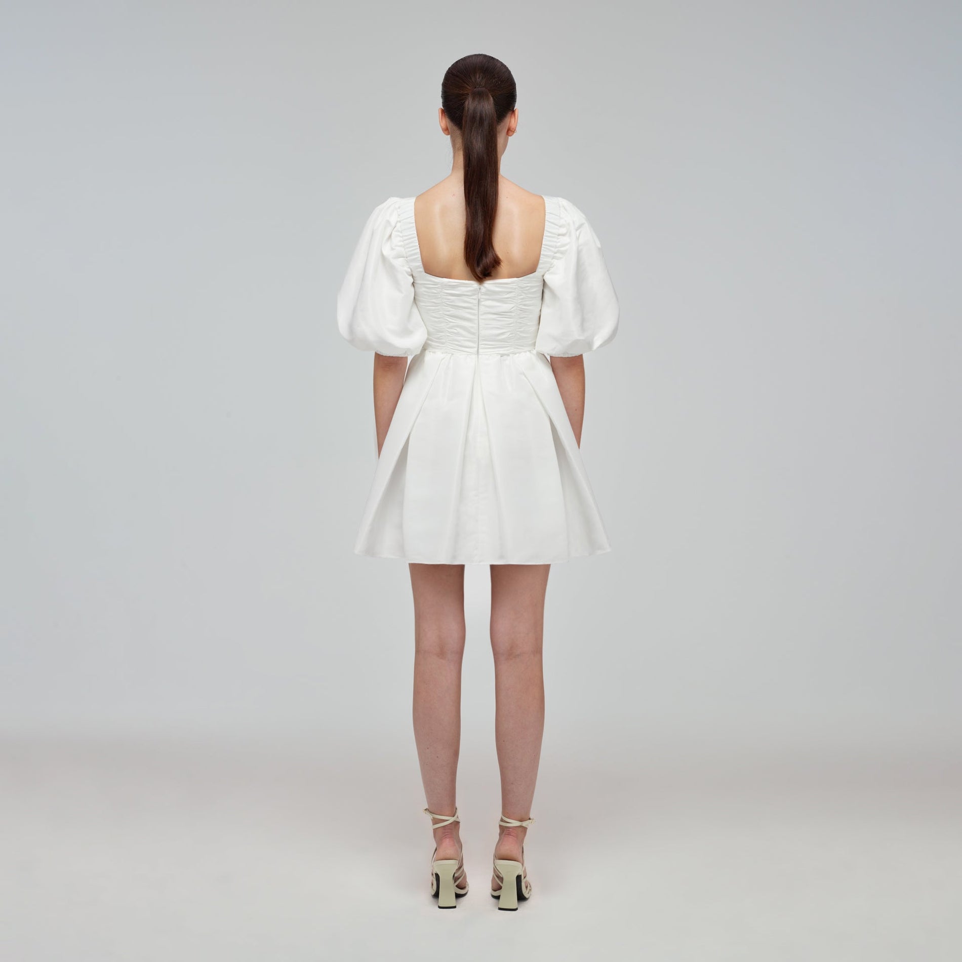 A woman wearing the White Taffeta Puff Sleeve Mini Dress